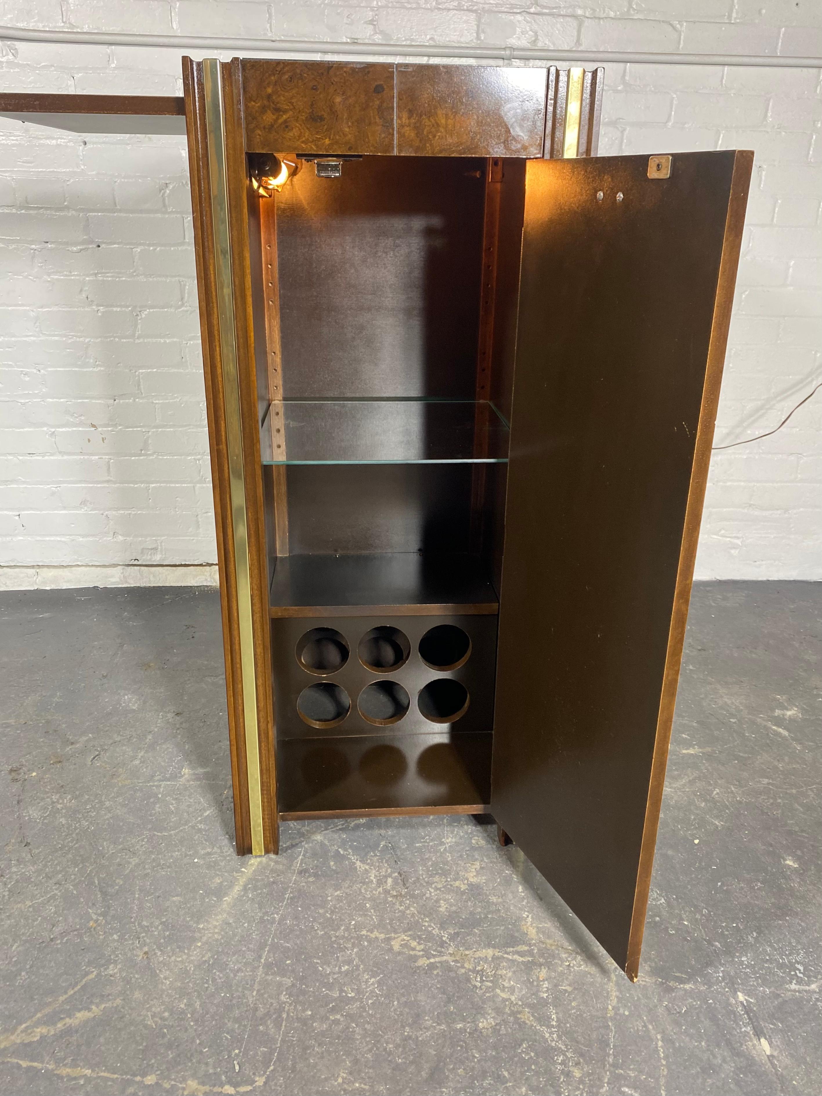 
Stunning Burl Wood and brass accents Dry Bar ,cabinet attributed to Milo Baughman. Black lacquer interior with glass shelf and lamp as well as pull-out cutting/ serving shelf.Interior bottom holds 6 bottles, Wonderful compact design. Hand delivery