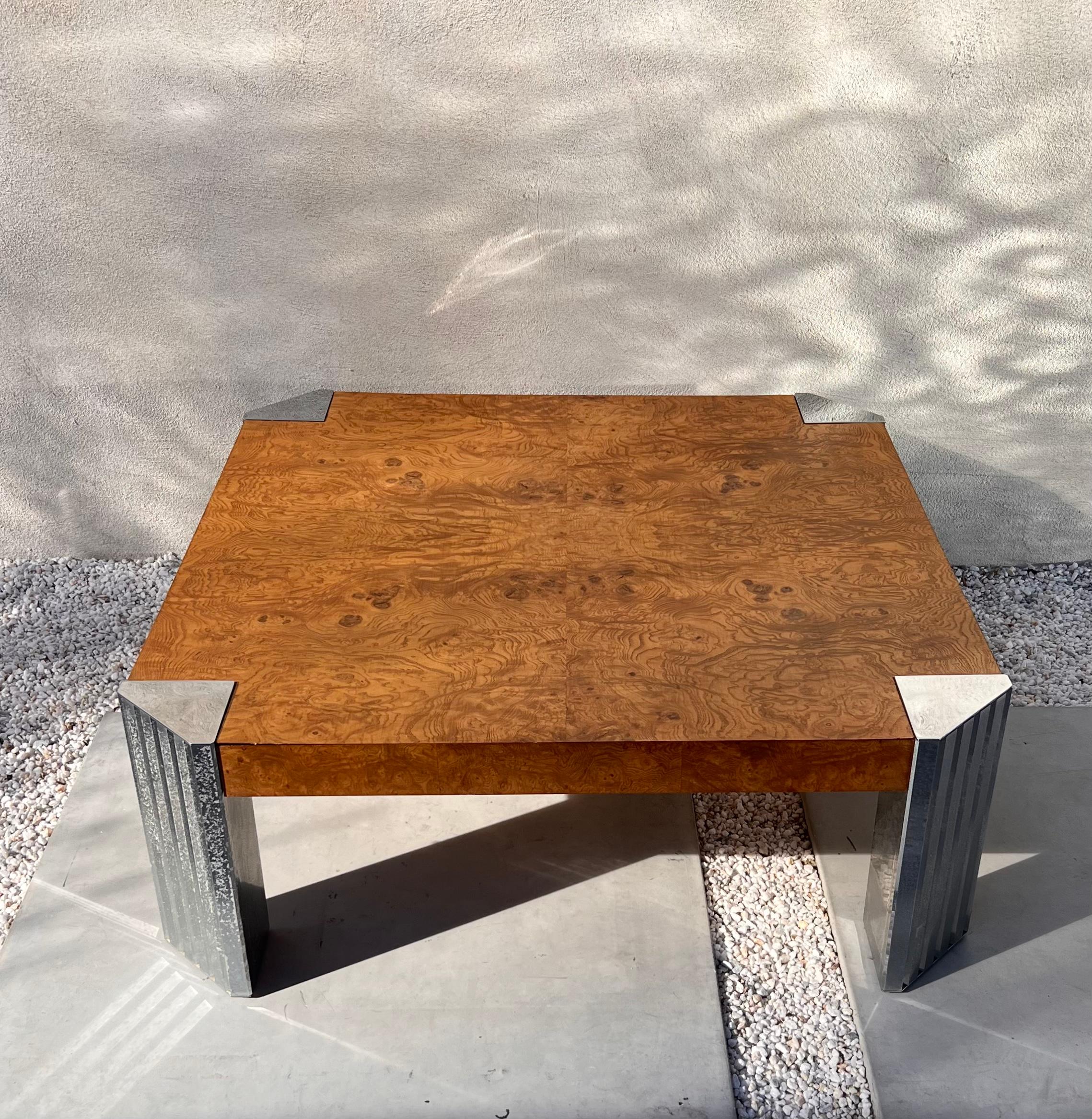 A coffee table by Rowe, circa early 1970s. In stunning burl wood and featuring chrome accents on each angled corner. Signs of age are minor but include a scuff and a small blemish on the top (these are both shown in photos). Overall wonderful