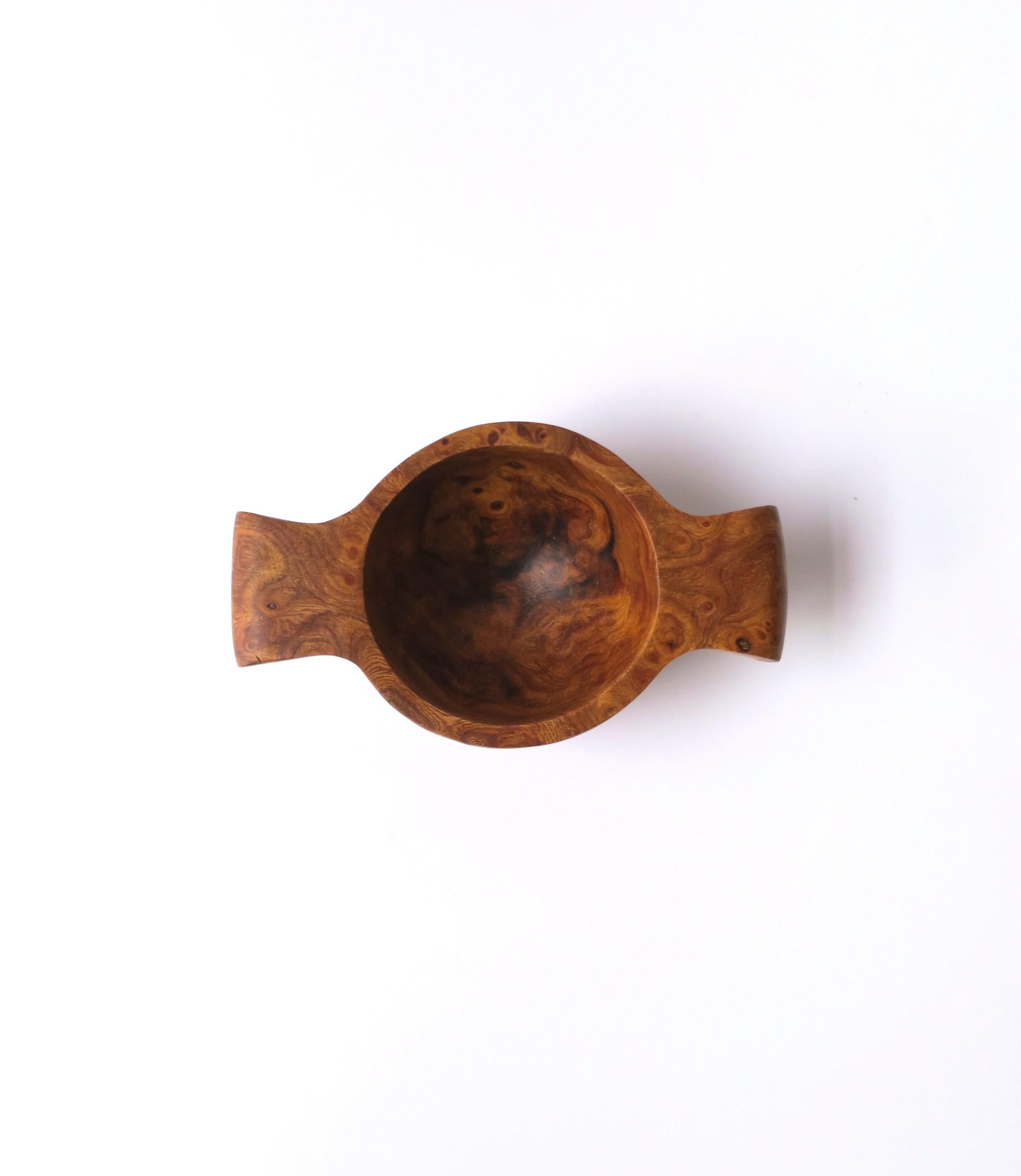 A small burl wood bowl with handles, organic modern/minimalist style, circa late-20th century to early 21st century. Piece is made from one piece of burl. Piece can hold small items on a vanity, desk, in a kitchen, etc. Shown holding earrings in