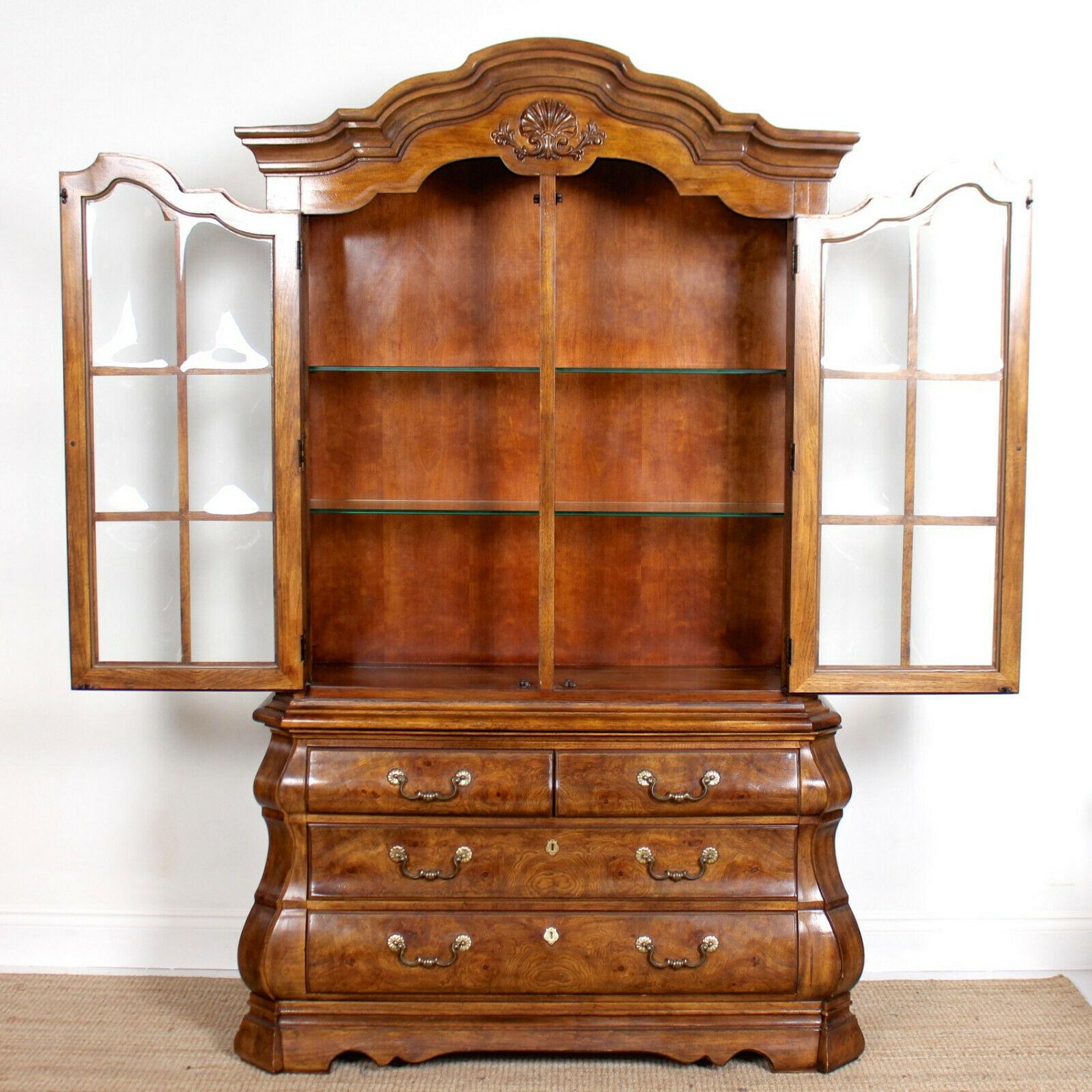 A fine quality spalted and figured burl elm glazed bombe display cabinet on chest by Drexel.

The upper section with arcaded moulded cornice and shell carved motif above bowed glazed paneled doors and ends enclosed interior lighting and glass