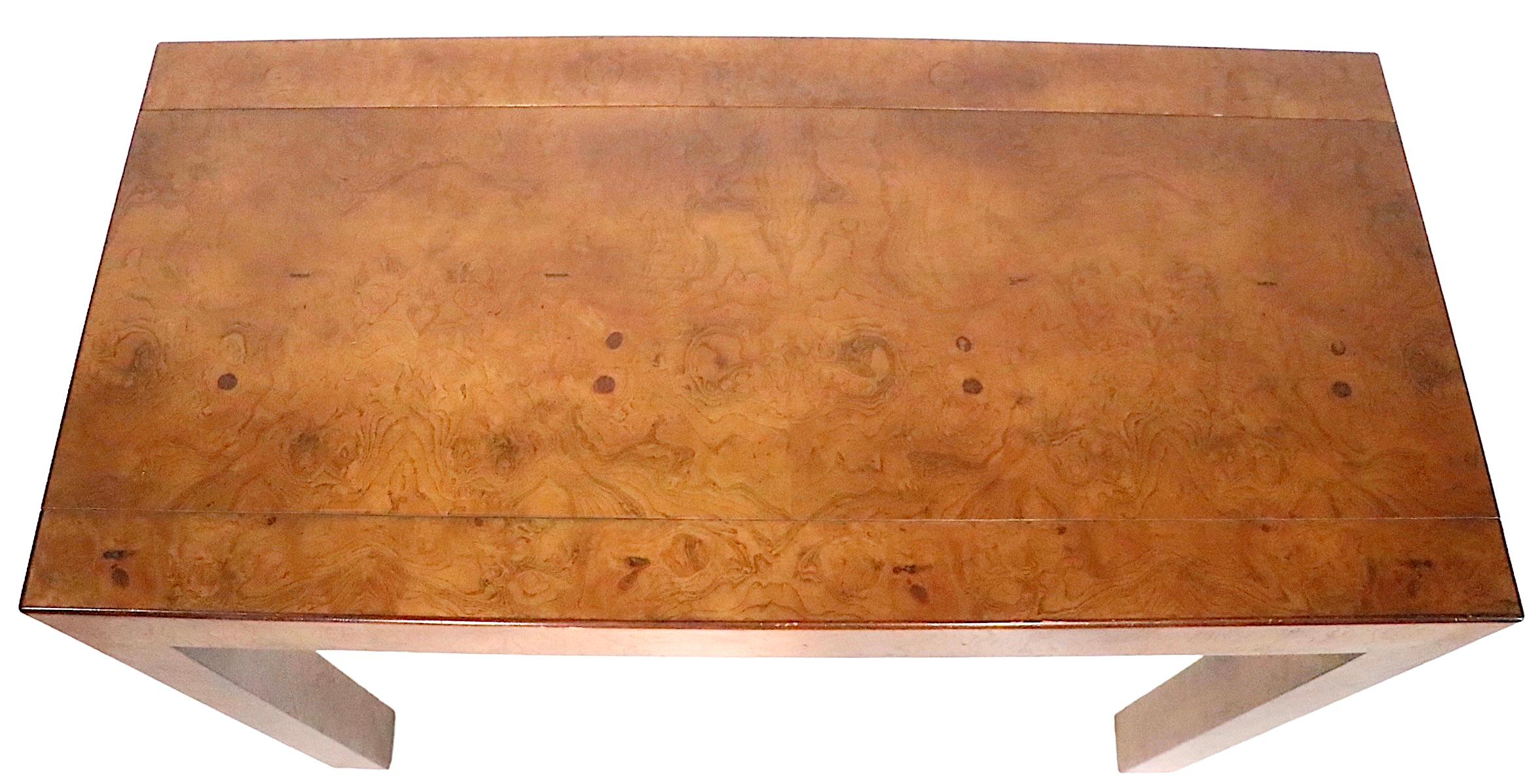 Chic burl Parsons style console table made by John Widdicomb, circa 1950-1960s. The table originally had many leaves which enabled it to function as a dining table, they are no longer present. 
Muscular chunky proportions, coupled with a voguish