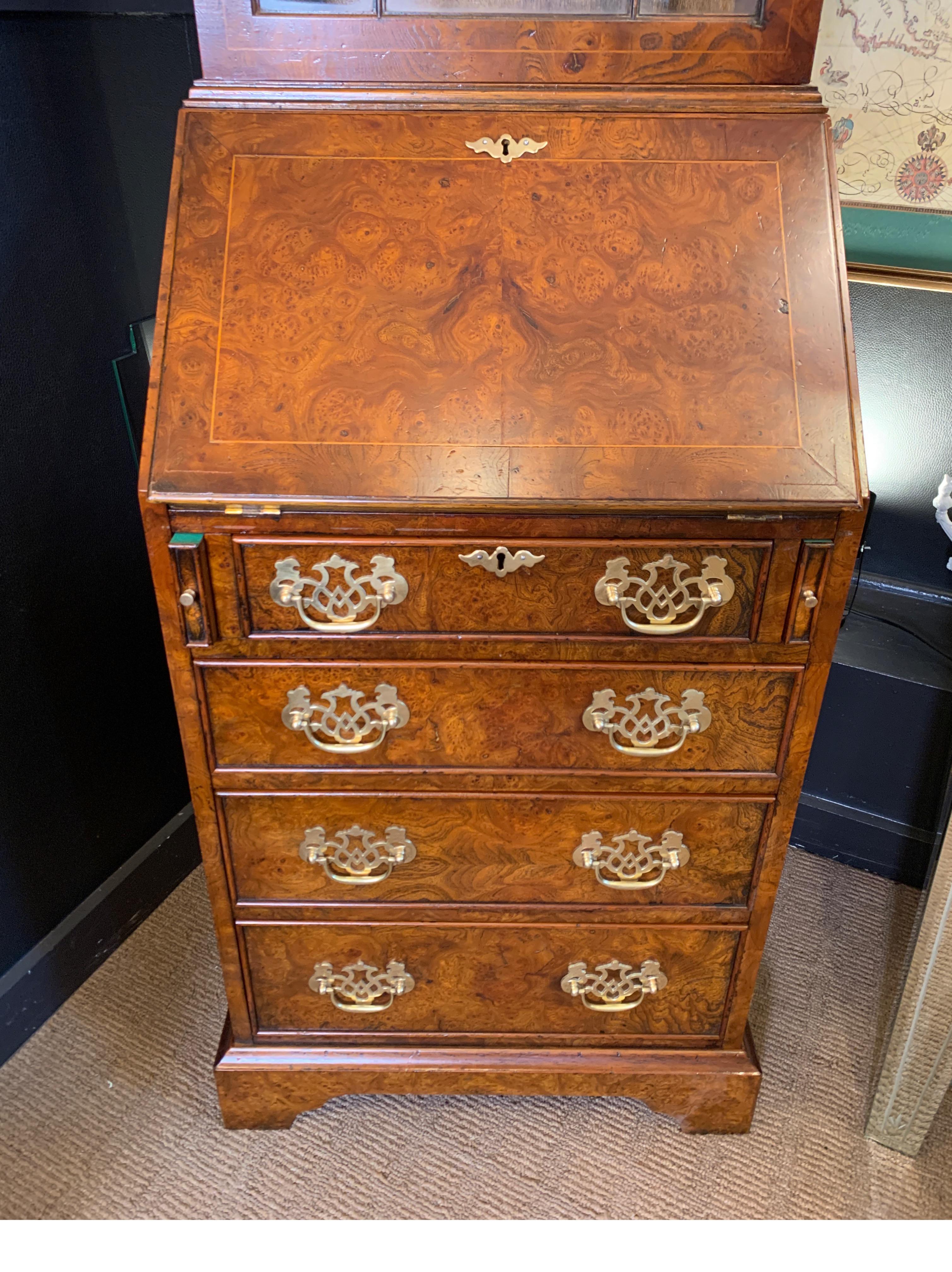A classic Chippendale style burl walnut secretary desk with bookcase top and fall front desk base. The solid brass pierced hardware with leather interior.