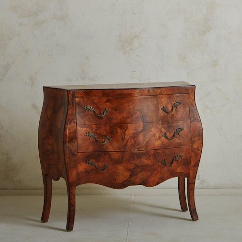 A 1960s Italian bombe chest of drawers with a gorgeously grained burl wood veneer. This piece has three drawers with curved metal leaf motif hardware and stands on delicately curved legs. Unmarked. Sourced in Italy, 1960s.