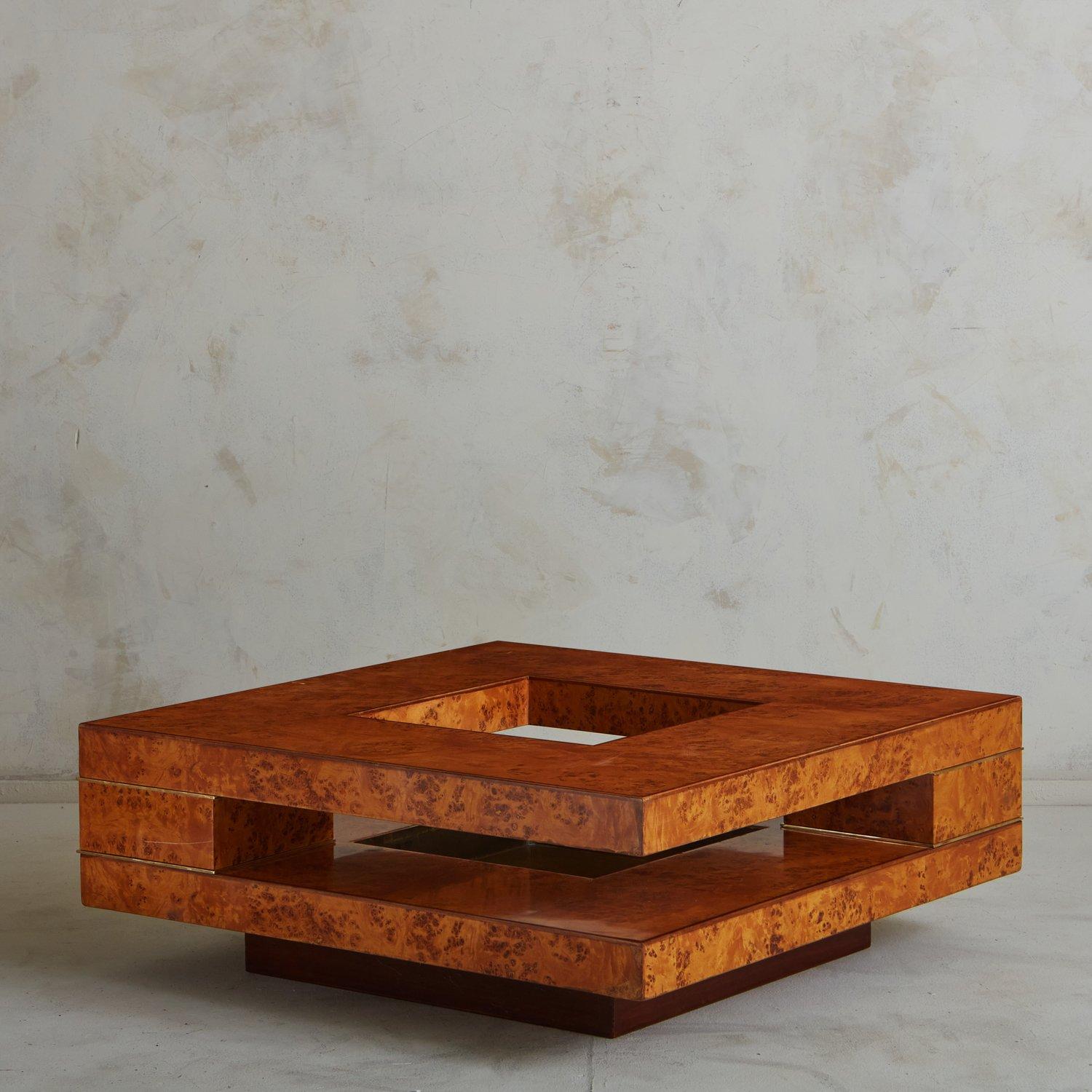 A sculptural 1970s coffee table attributed to Willy Rizzo. This table features a lacquered burl wood veneer with beautiful graining and subtle brass detailing. It has a two-tier top with cutout details along the sides and top, perfect for styling