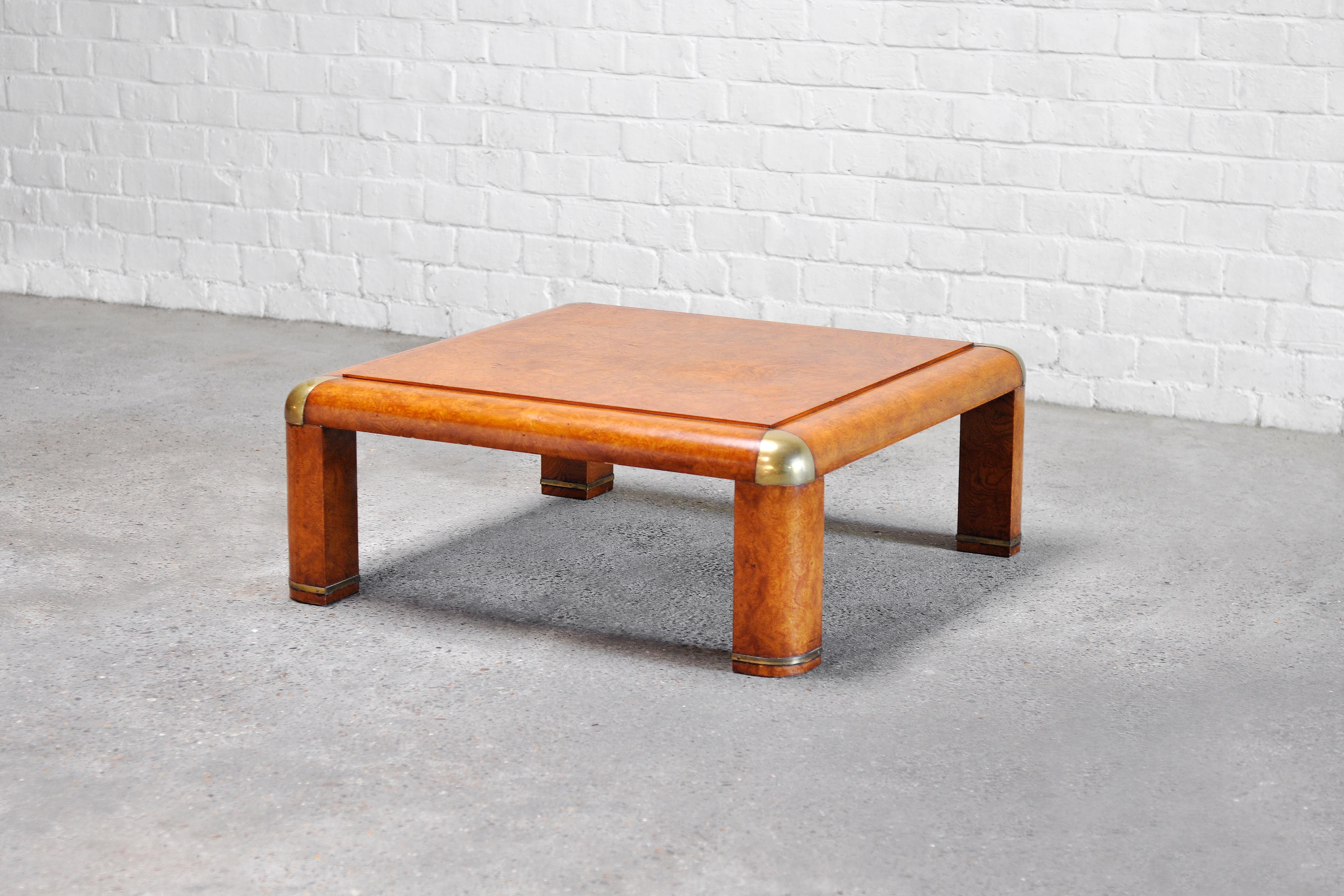 A unique burl wood coffee table with large brass accents. This table dates to the 1970's and is attributed to Karl Springer due to its typical matching design features. It has a low and playful design finished with thick rounded table legs and