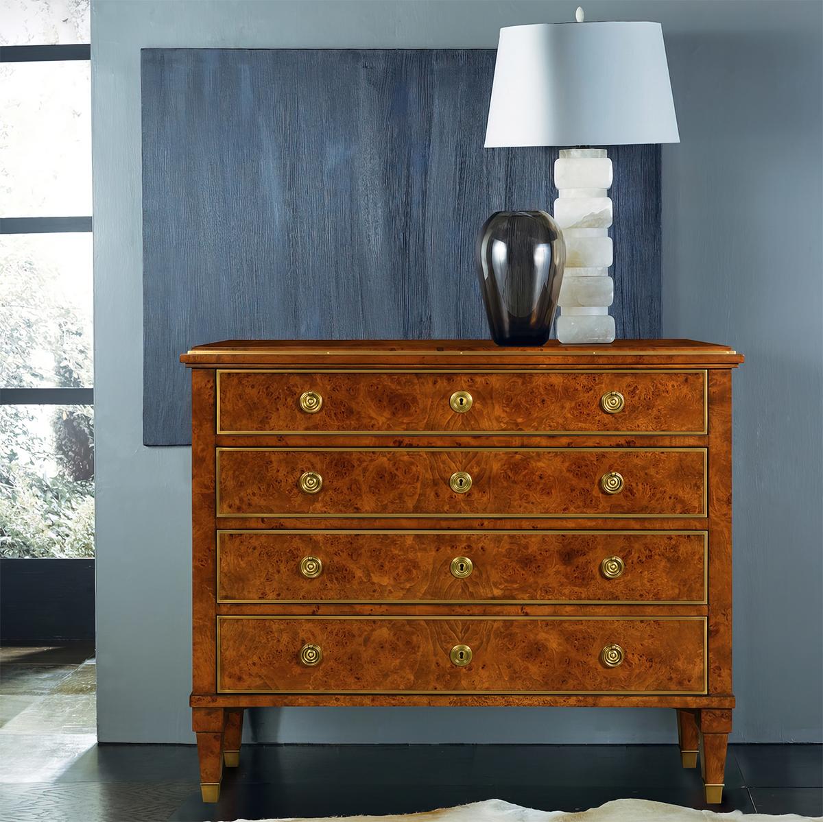 The four-drawer chest is wrapped in a gorgeous Birch burl veneer. An exotic figured wood with a high polish to highlight the movement and unusual details. The rectangular top and drawer fronts are framed with solid brass trim and the drawers have