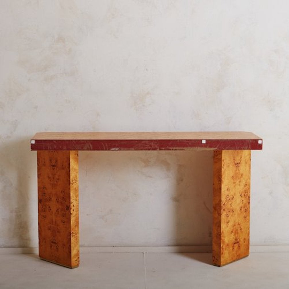 A French burl wood console table featuring gorgeous wood graining. This table has a rectangular tabletop and stands on two angled, rectangular block legs with brass feet and brass detailing along the top. Sourced in France, 20th century.