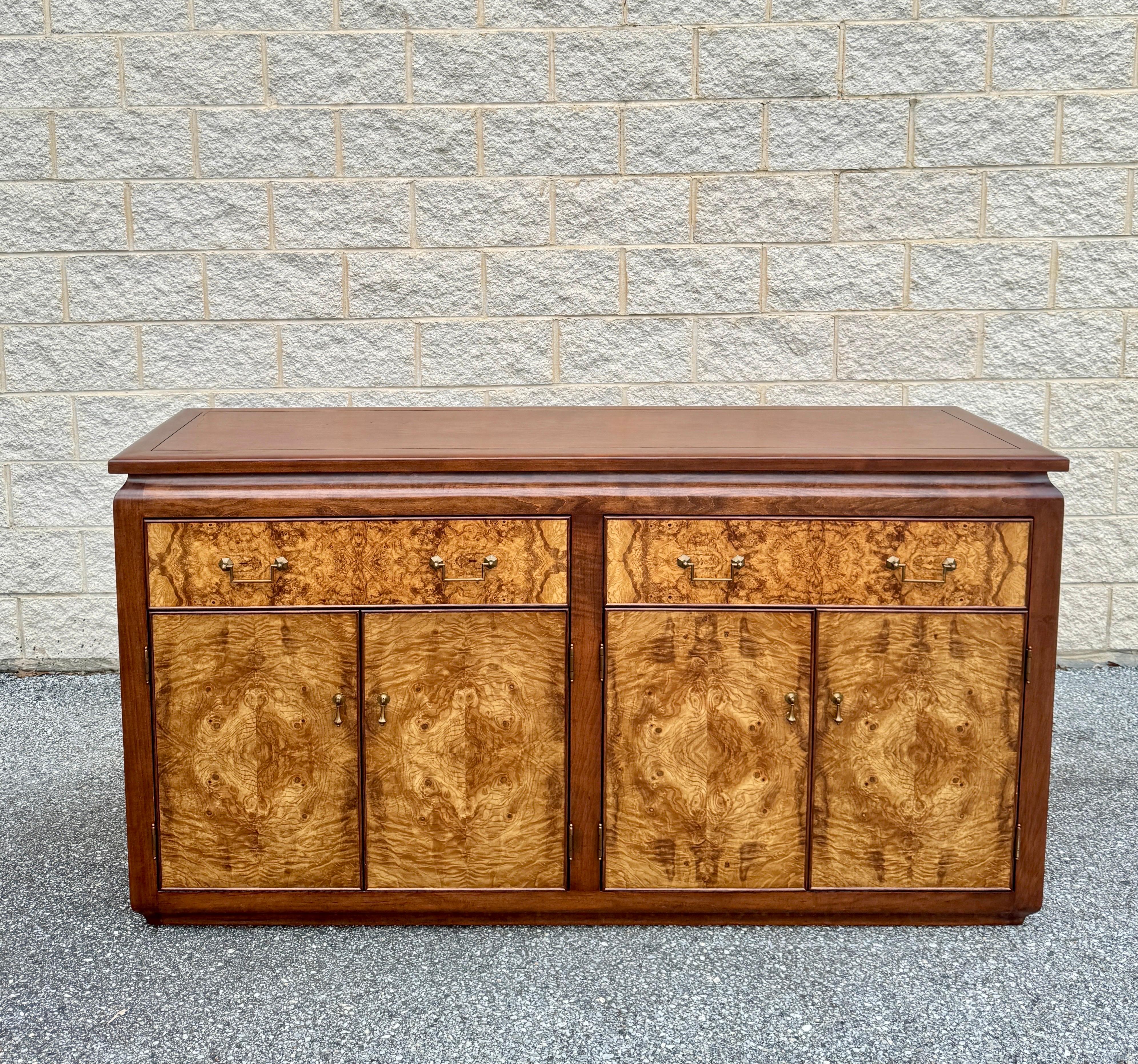 The credenza is meticulously crafted from burl wood and rosewood, adorned with elegant brass handles. It features two generous interior drawers for ample storage, along with two double-door compartments equipped with flexible shelves for versatile