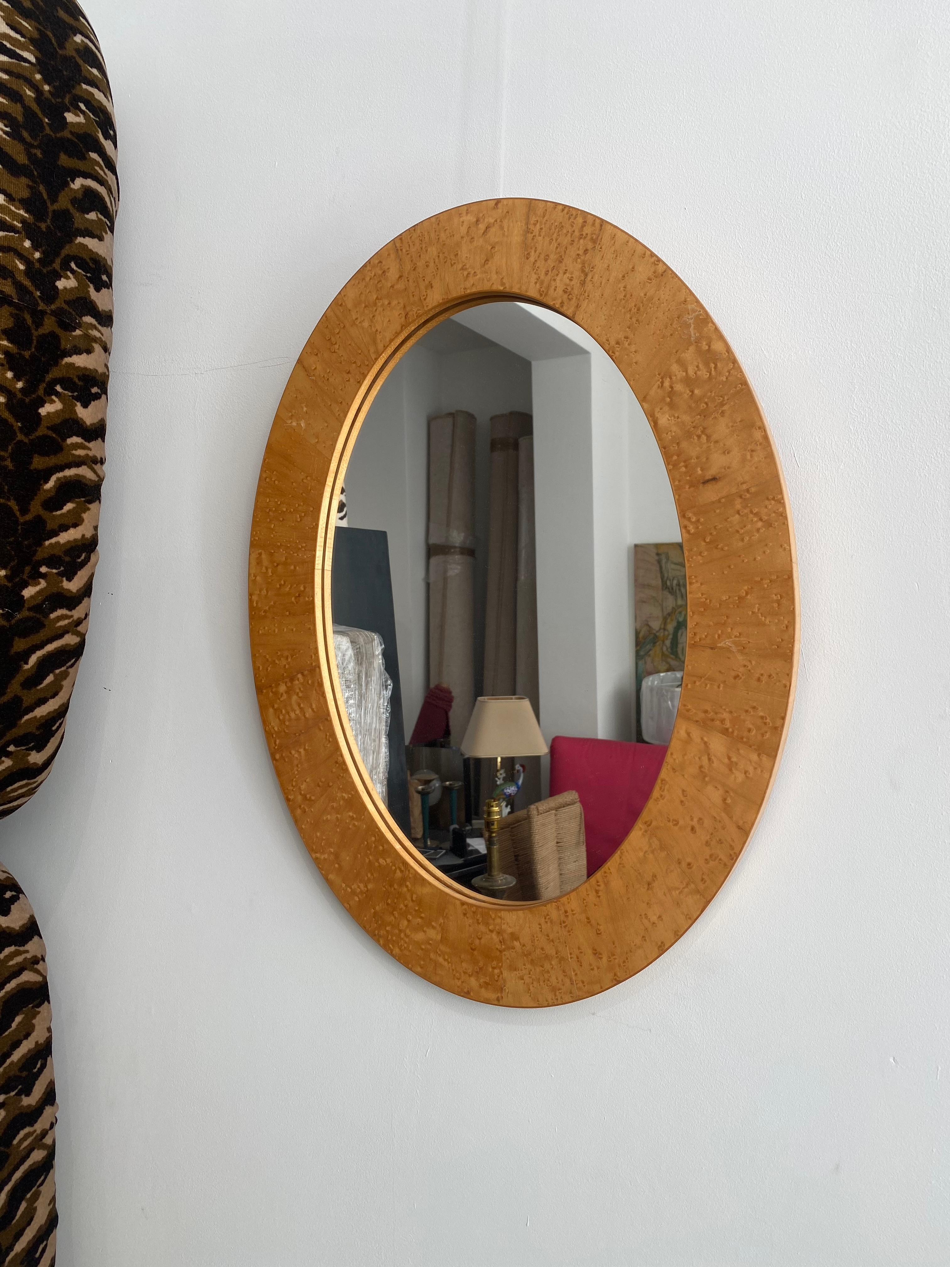 Miroir ovale dans un cadre en placage de bois de ronce assorti à un livre. Le cadre a été fabriqué au début des années 1970 et rappelle la période art déco. Le miroir lui-même est relativement récent et a été remplacé en 2010. 

Très belle pièce qui