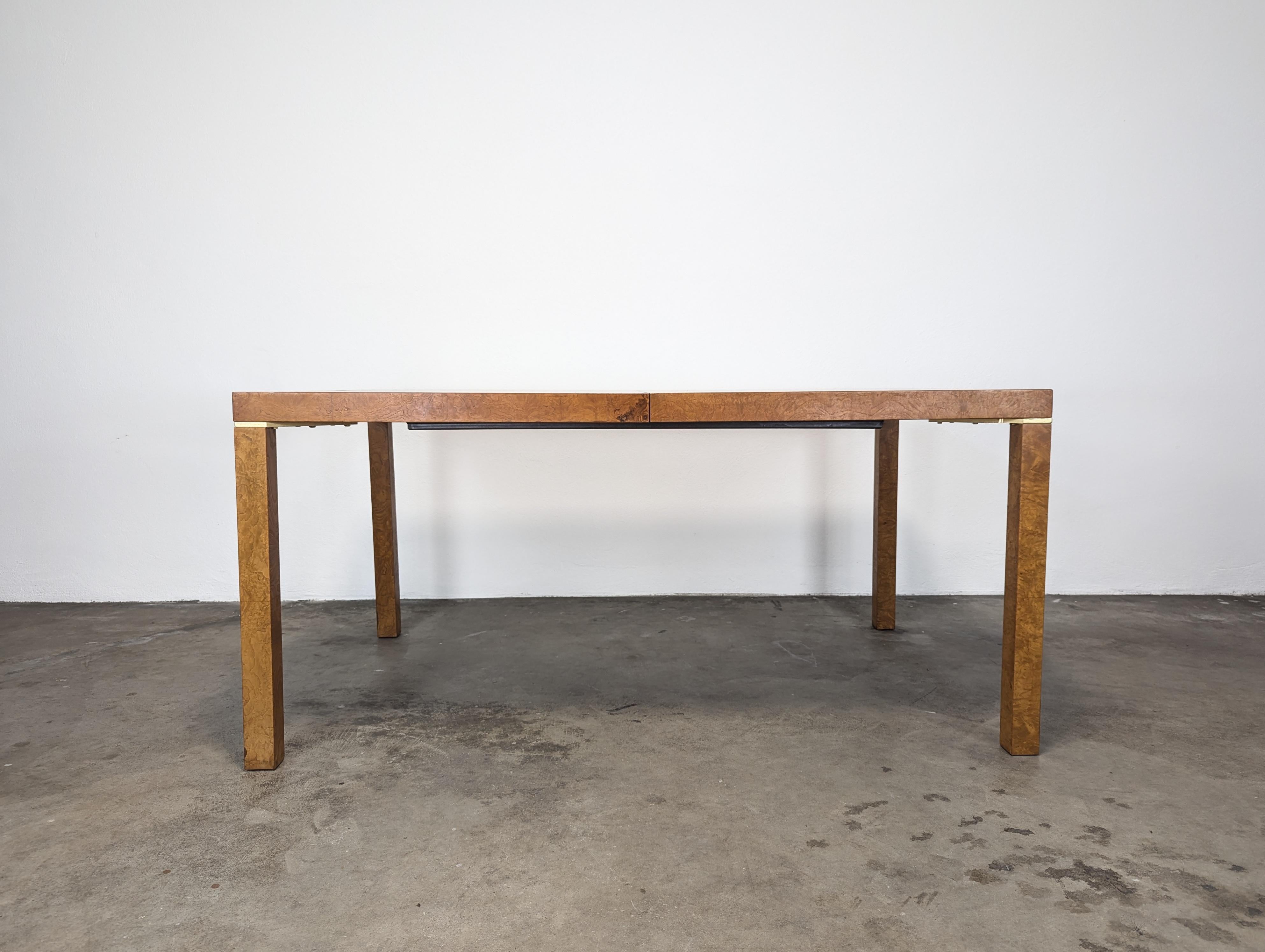 For sale is a stunning Mid-Century Modern Parsons-style dining table, crafted with exquisite bookmatched olive ash burl wood, reminiscent of the iconic designs by Milo Baughman. Created by the renowned Lane Furniture in the 1970s, this table