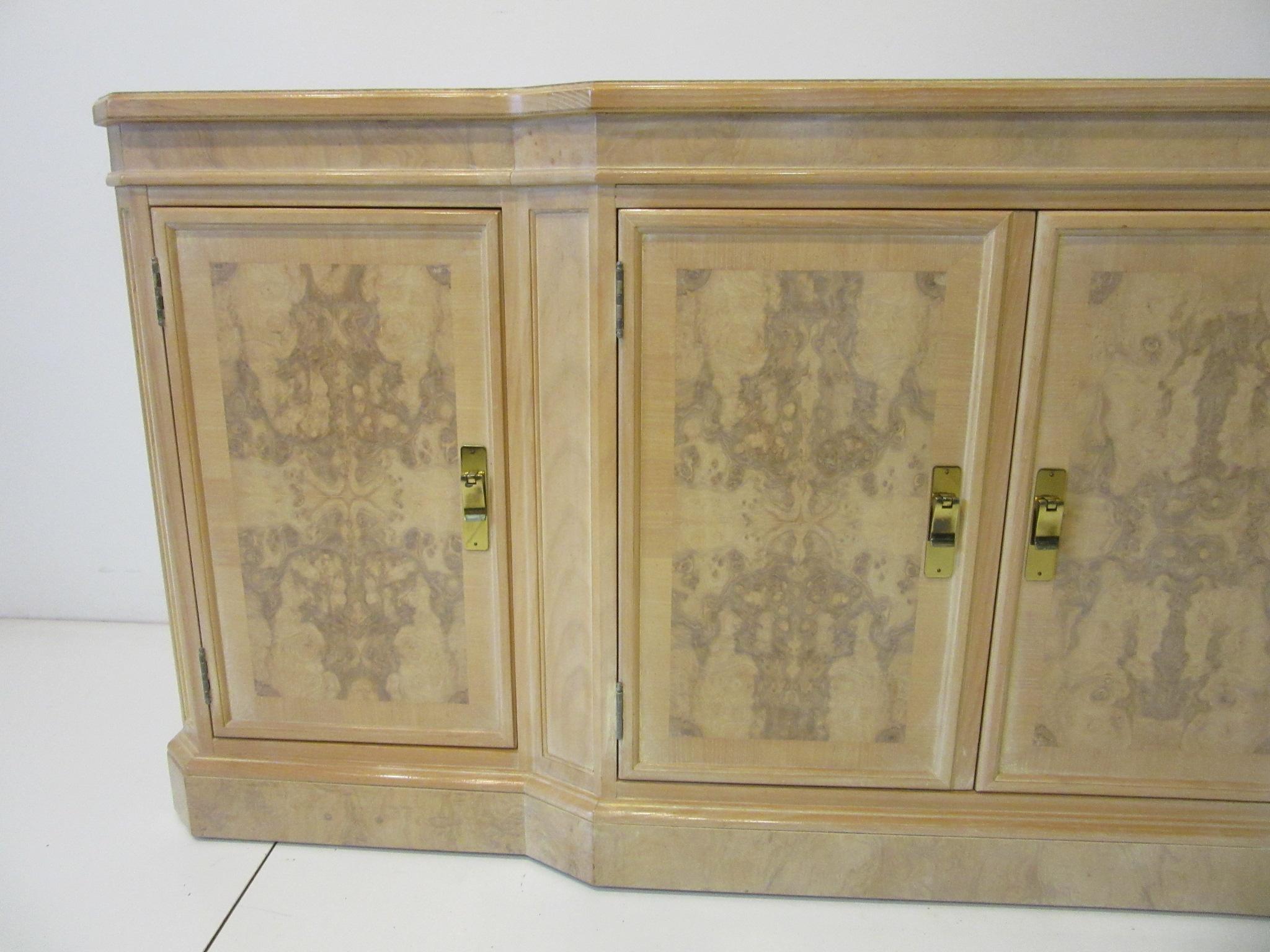 A very well crafted bookmatched olive and ashwood server cabinet, two doors to each end with adjustable shelve and two center double doors having three drawers all with heavy brass pulls. Retains the manufactures label to the drawer by the Heritage
