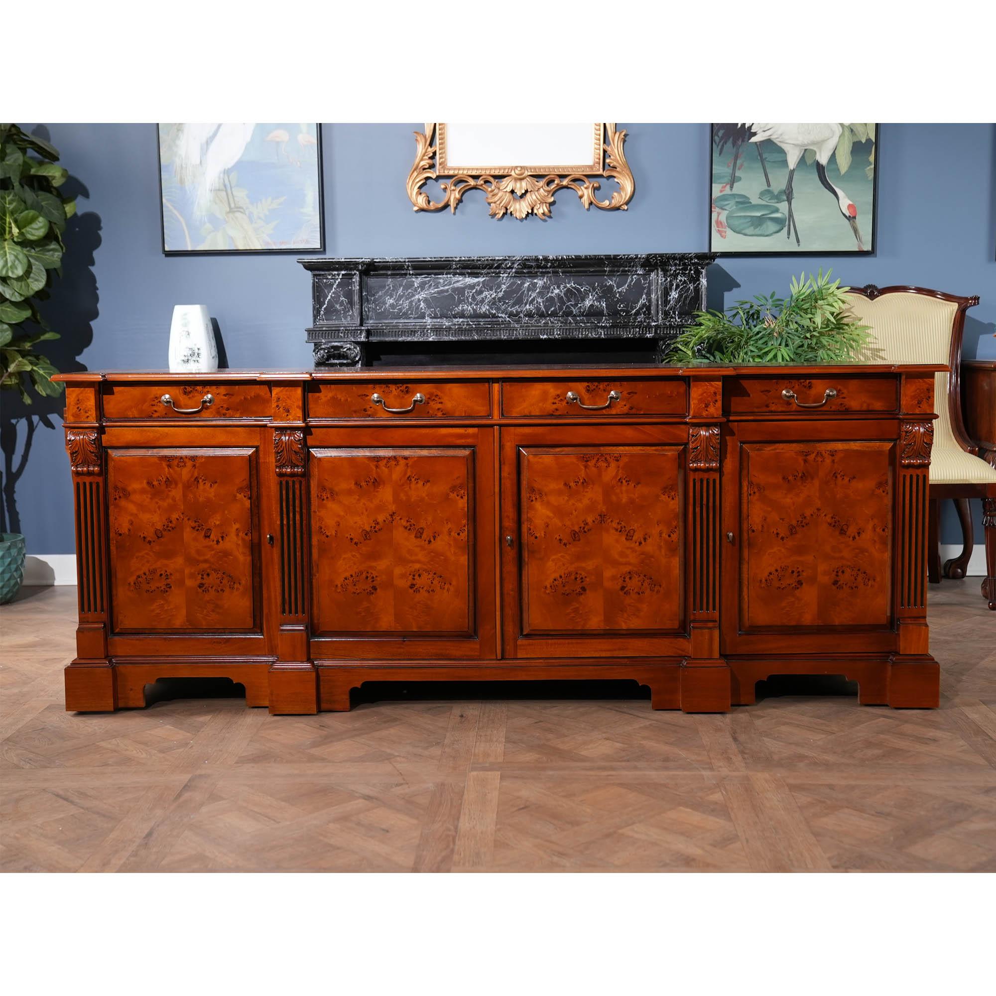 Our Burled Breakfront is manufactured in two sections, the upper section consisting of a deep, molded cornice with burled veneer following the shape of pillars rising from below, with acanthus carved capitals atop four doors with shaped, open glass