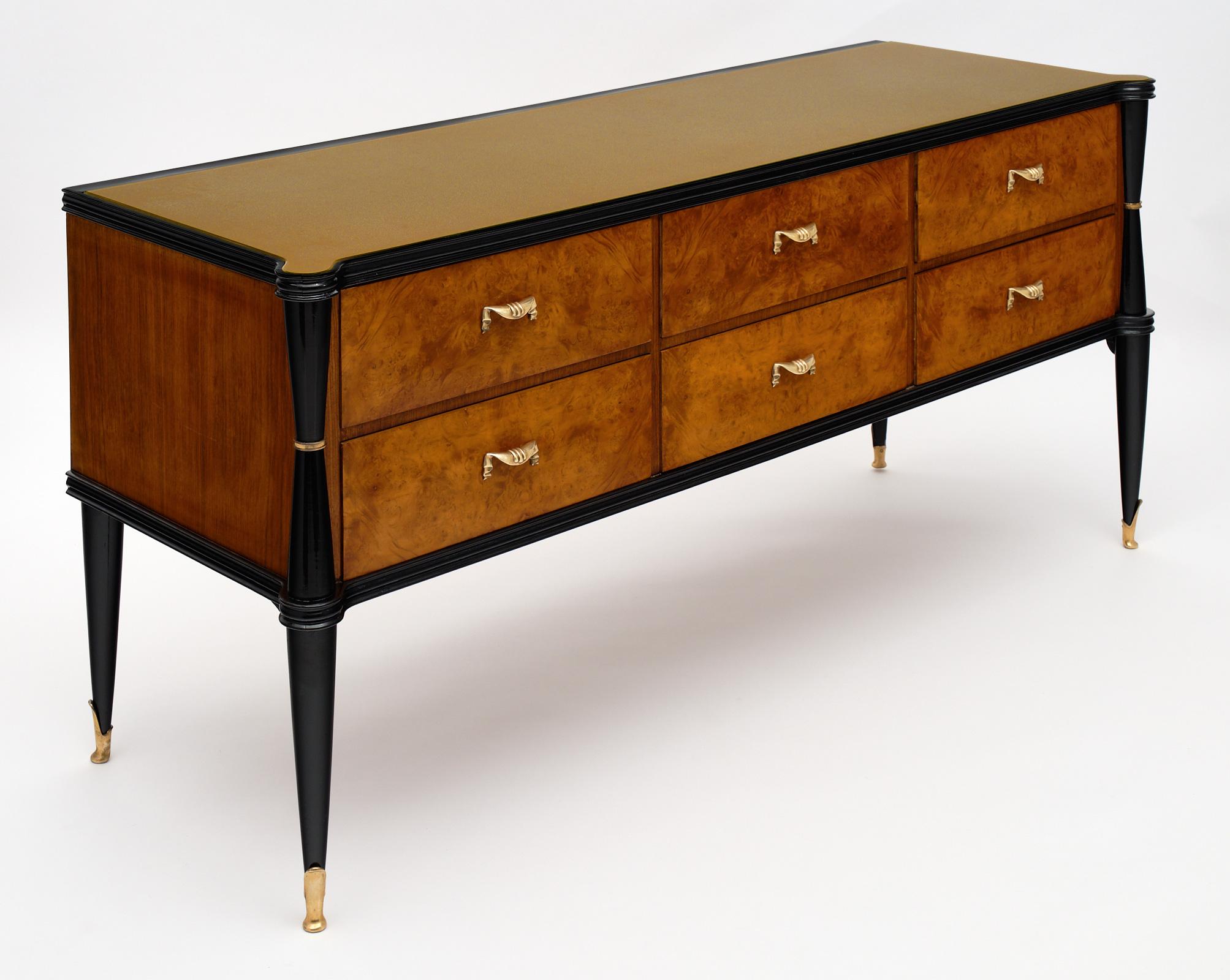 Italian burled walnut chest of drawers in a modernist style. We love the ebonized frame and warmth of this piece. The six dovetailed drawers featuring their originally case gilded bronze hardware and feet. We love the champagne colored glass on top