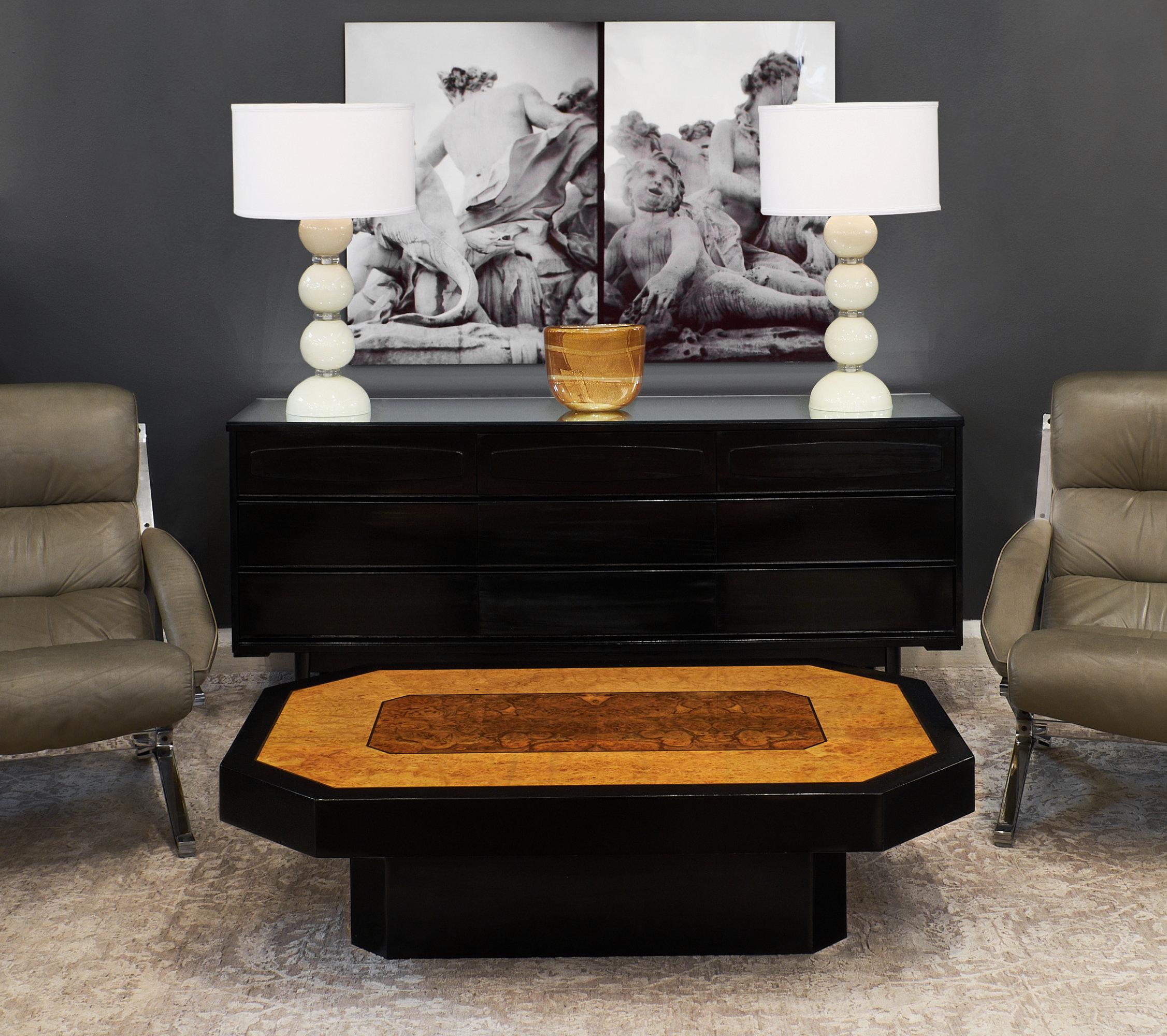 In the manner of Willy Rizzo, this Italian burled wood coffee table coffee table boasts a striking combination of burled ash and elm woods with an ebonized base and frame. The finish is a high luster French Polish.