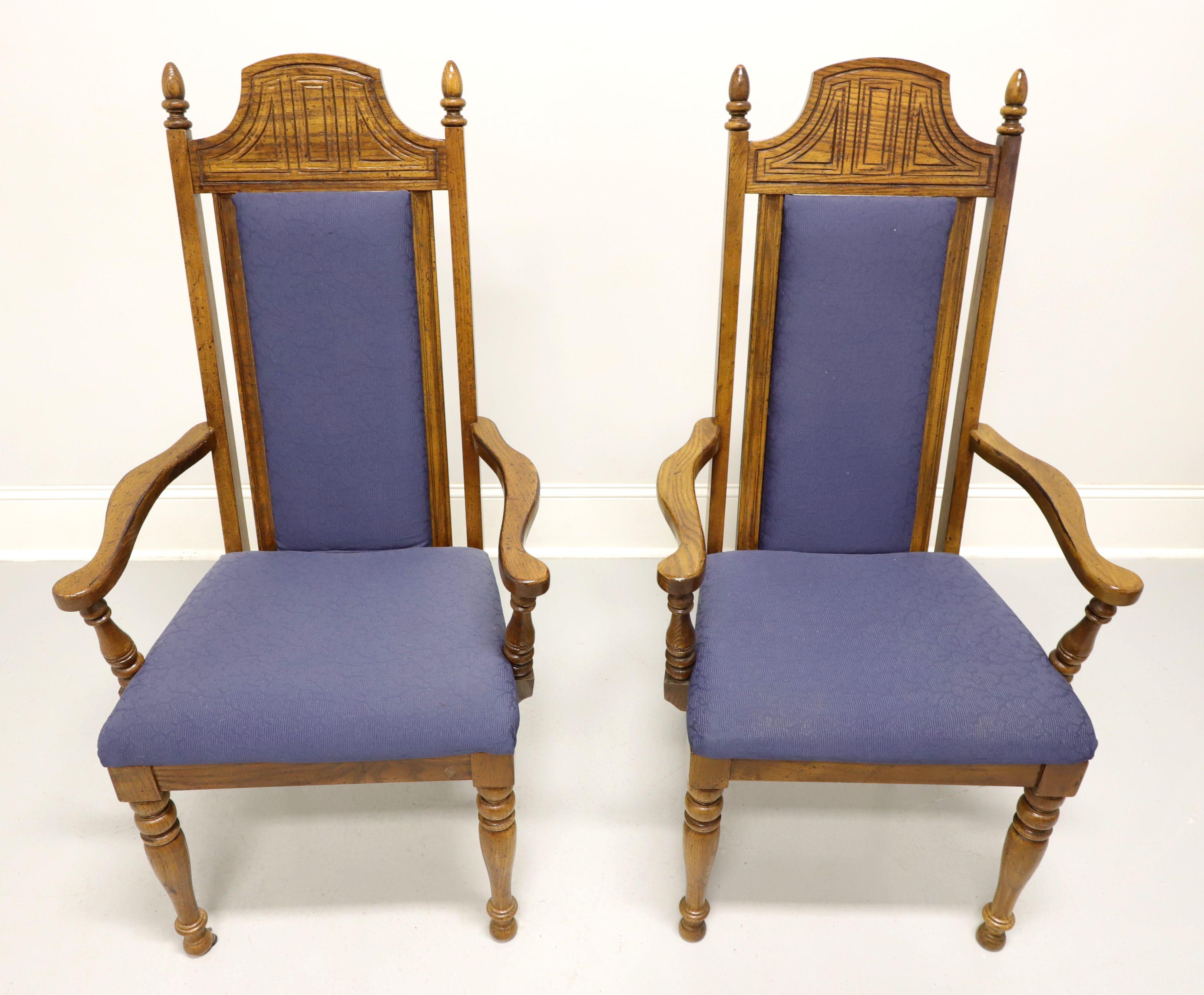 A pair of Spanish Revival style dining armchairs by Burlington House. Solid oak with distressed finish, high backs with rounded solid carved crest rail, square stiles with finial ends & blue color fabric upholstered center back rest, curved arms