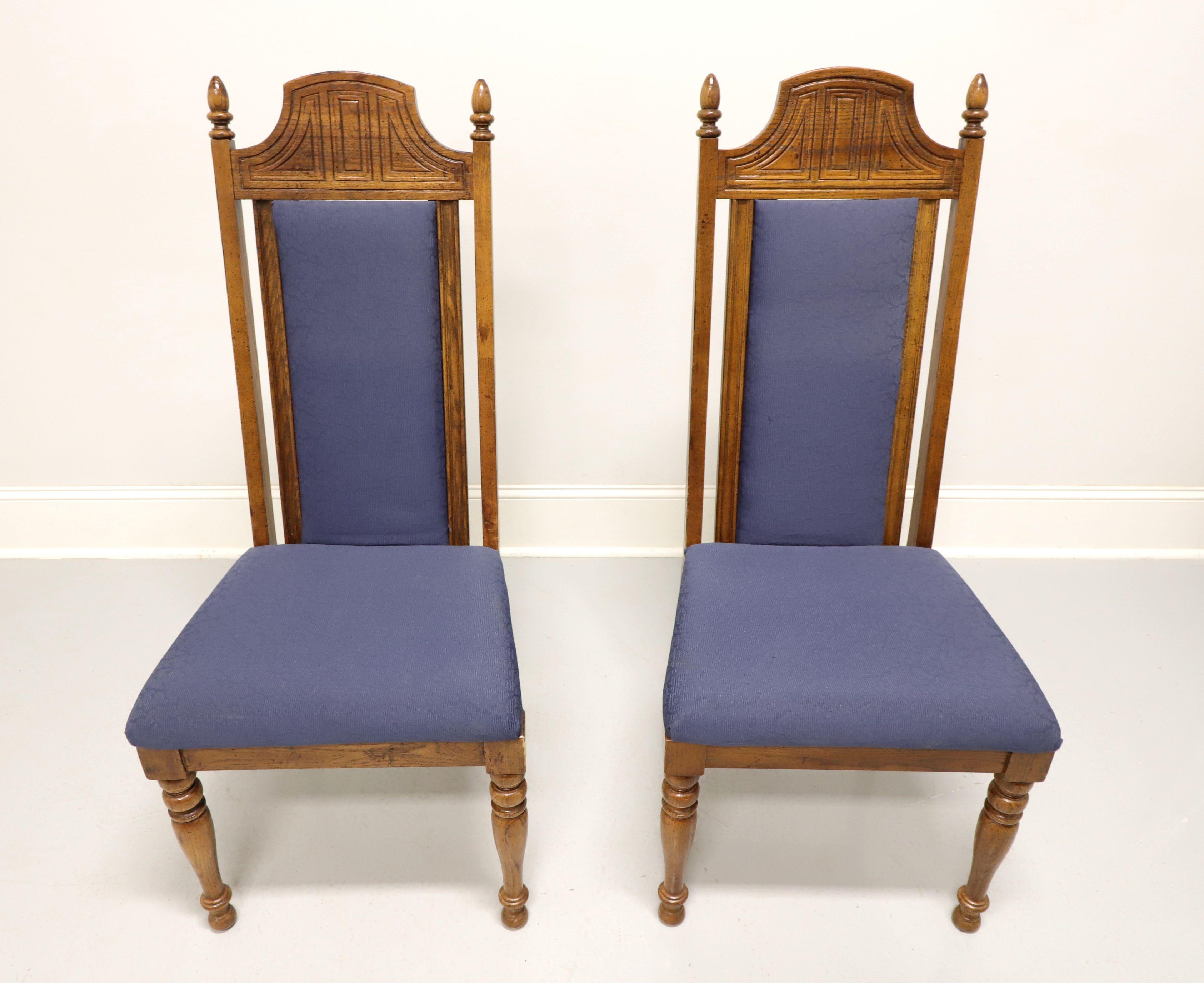 A pair of Spanish Revival style dining side chairs by Burlington House. Solid oak with distressed finish, high backs with rounded solid carved crest rail, square stiles with finial ends & blue color fabric upholstered center back rest, blue color