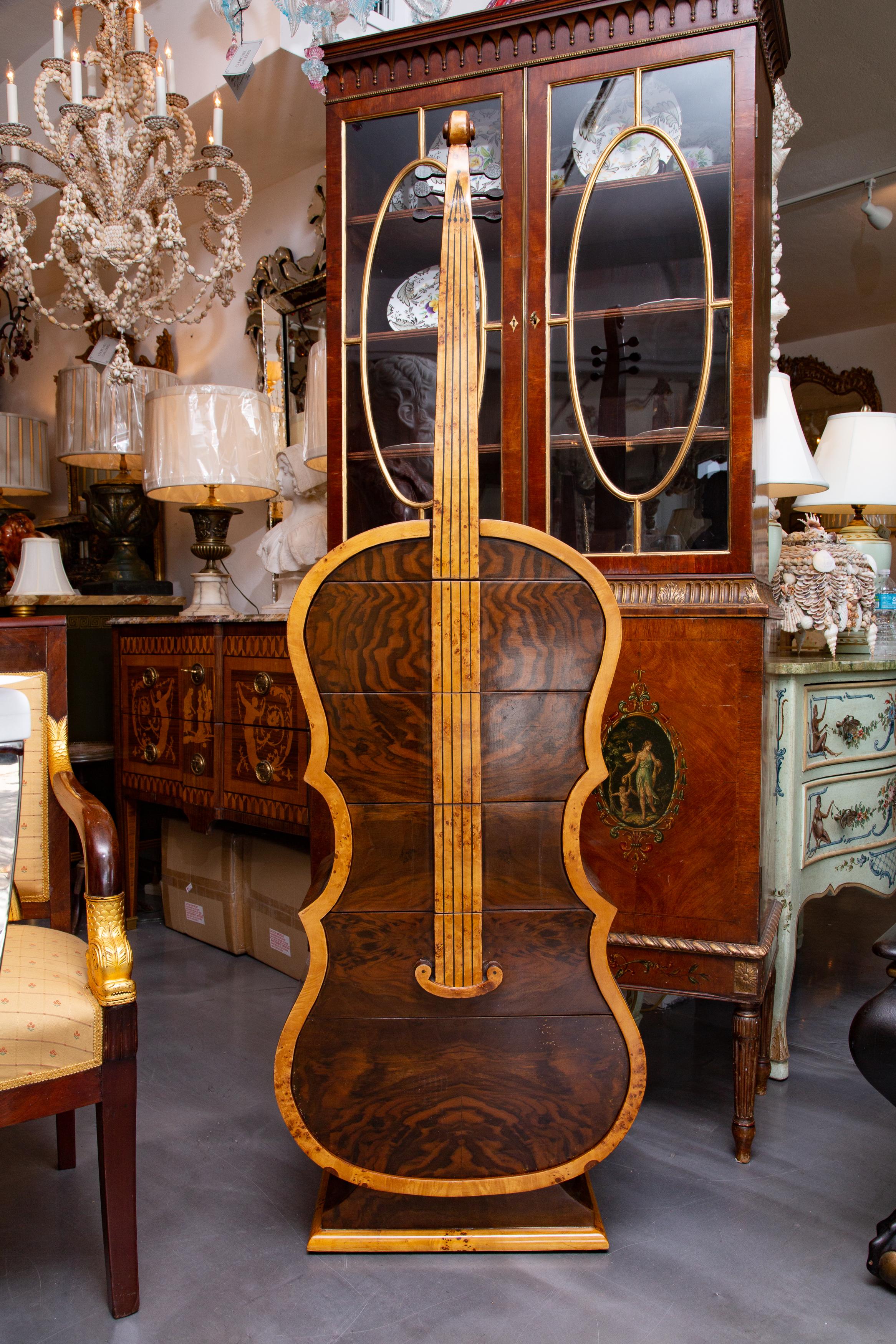 This is a very unique burlwood cabinet in the form of a cello with neck and fingerboard. the cabinet contains a bank of four operable drawers, 20th century.