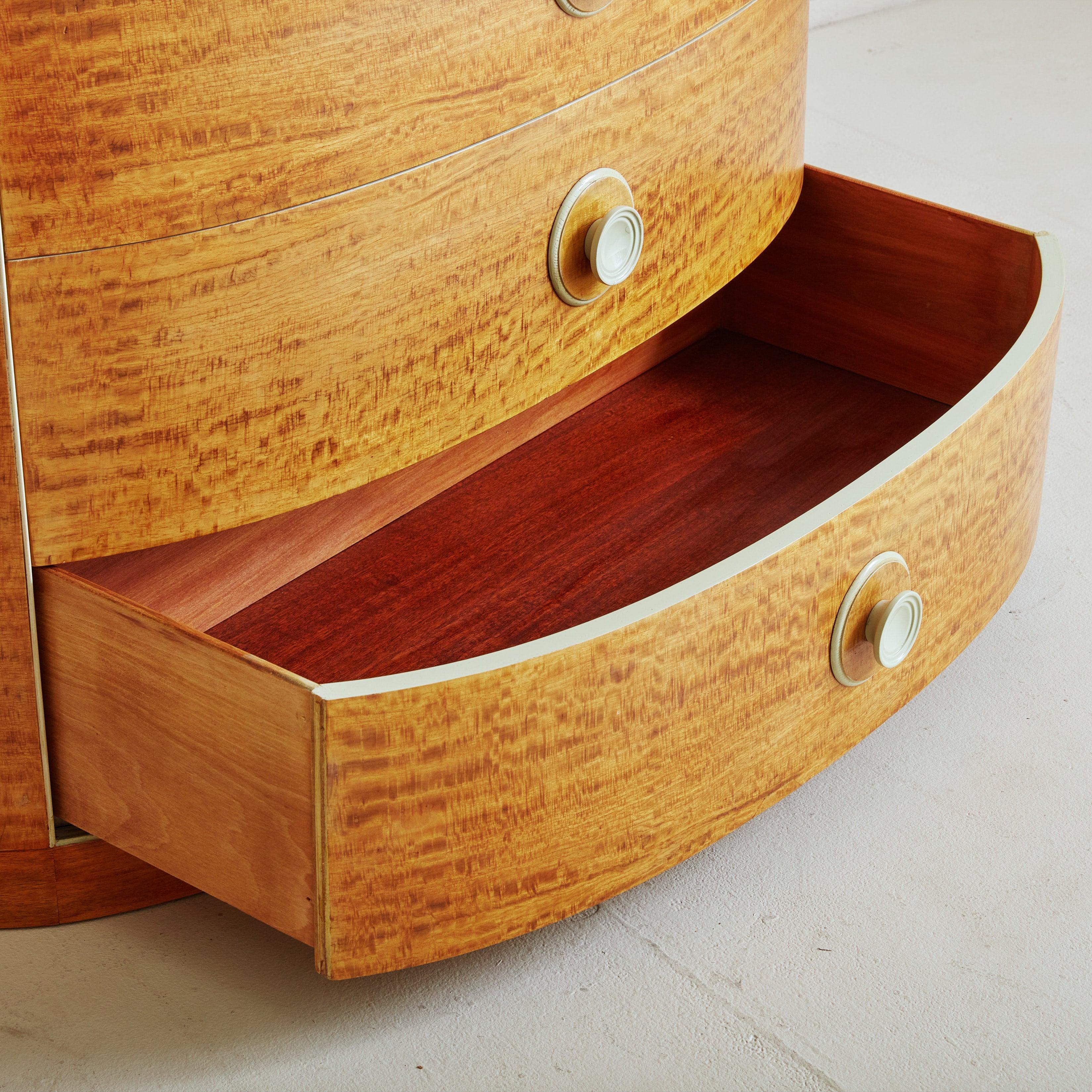 A 1970s Italian chest of drawers in the style of Osvaldo Borsani. This piece is constructed of gorgeous burl veneer in a warm, honey finish. The curved silhouette features a demilune surface and three drawers adorned with oversized off-white