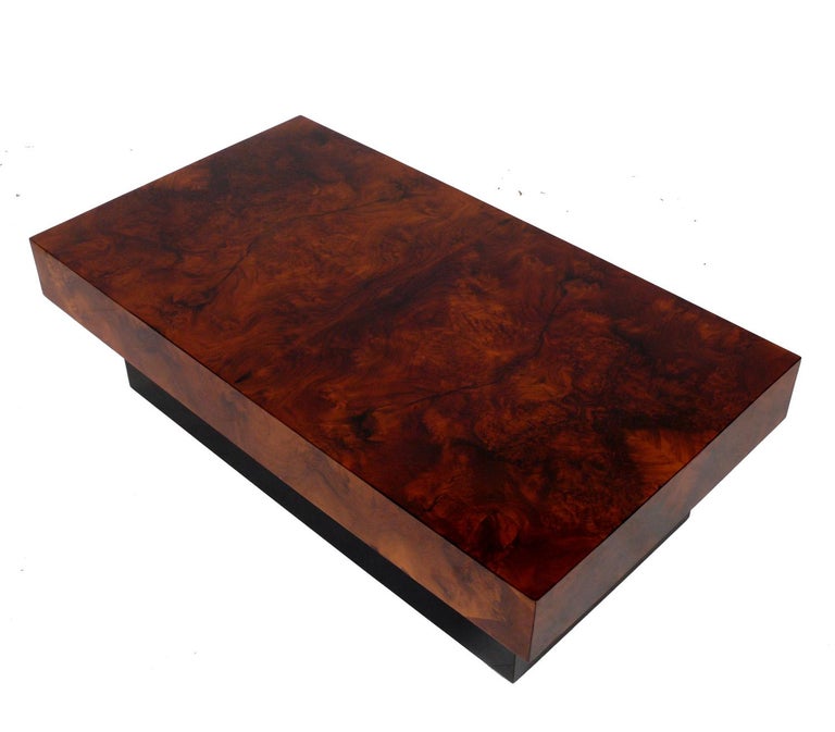 Clean Lined burl wood coffee table, attributed to Milo Baughman, circa 1960s. It is constructed of a burlwood top floating over a black lacquered wood base.