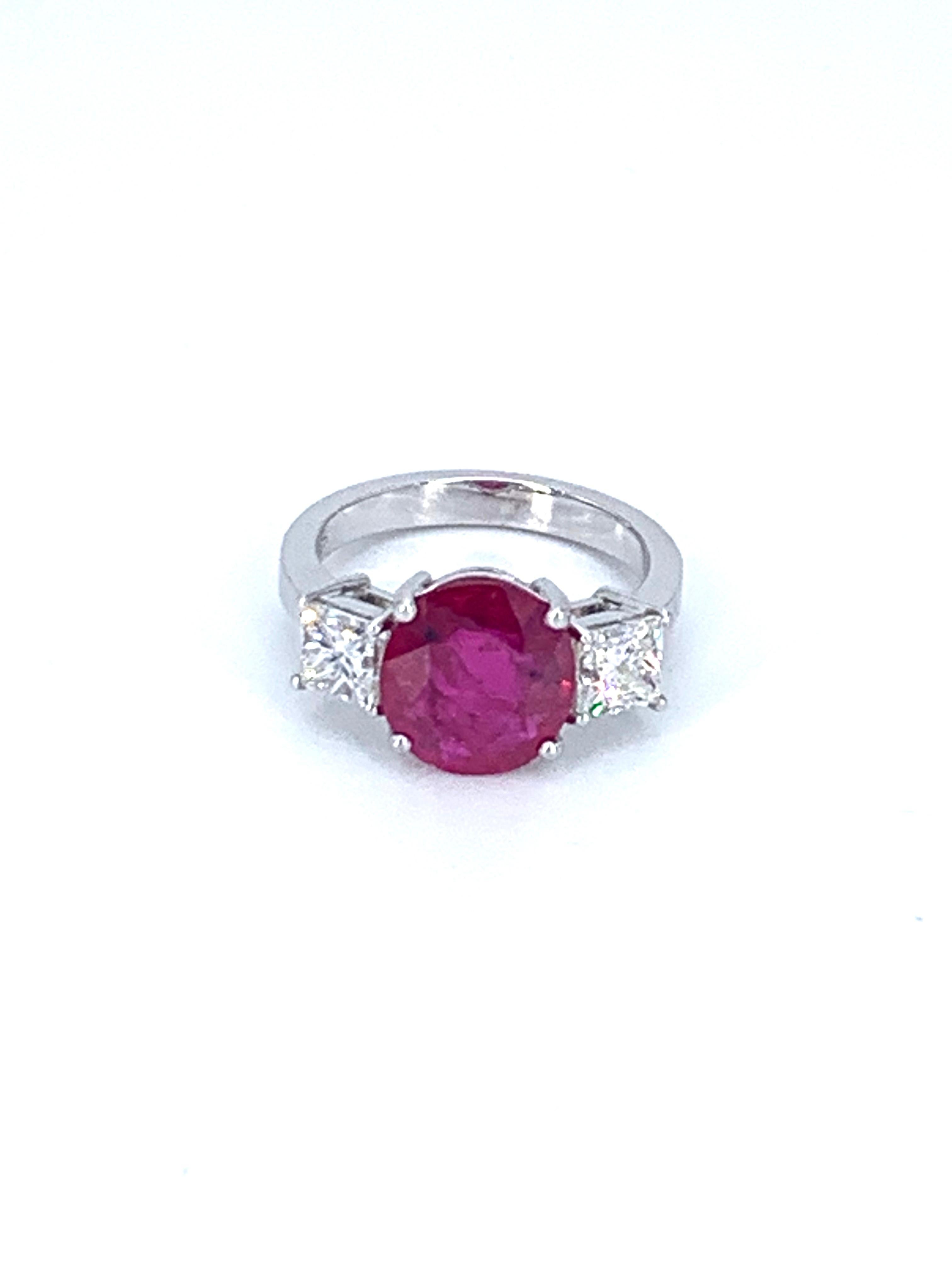 This natural Ruby from Burma is 3.27 Carats & with the 1.41 Carat diamond, it radiates a beauty indescribable in words.

The round red Ruby sits boldly in the center of the ring with 2 princess cut natural white diamonds either side amounting to