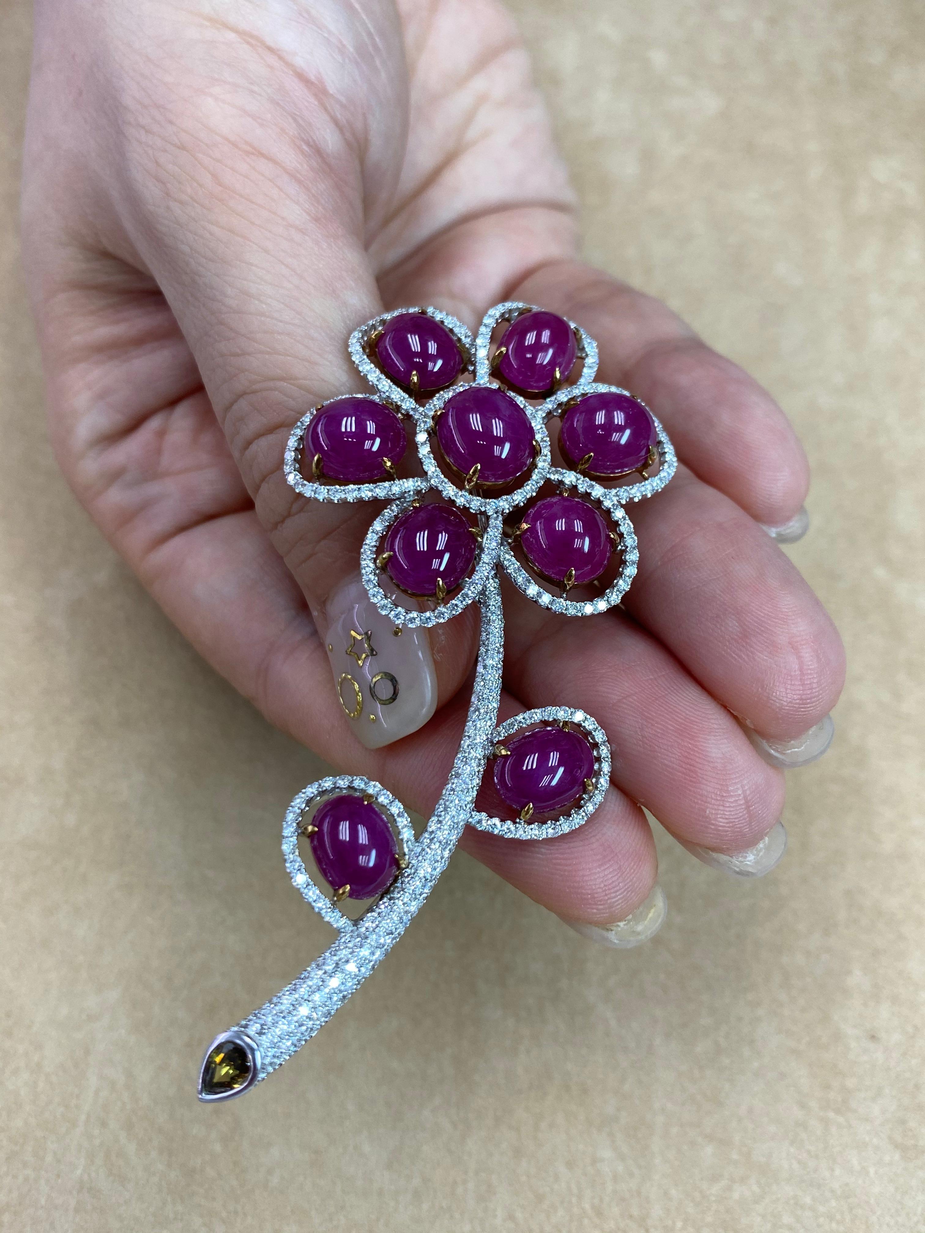 Here is a nice Ruby and diamond brooch. The brooch is set in 18k white gold, white diamonds and one fancy colored pear shaped diamond. . There are 9 Burma ruby cabochons totaling 26.48 Cts. There are 314 small diamonds totaling 2.47 cts in this