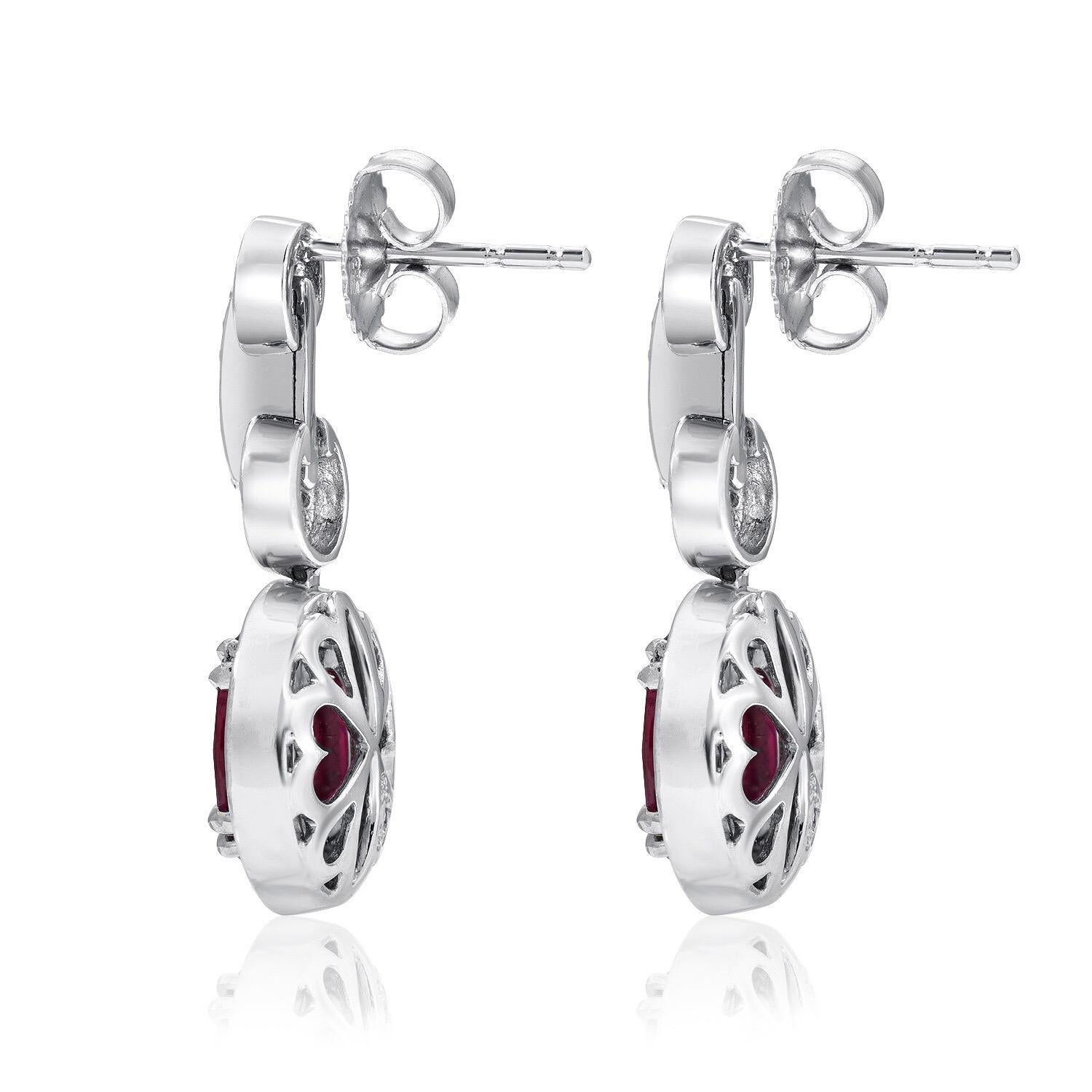 Burma Ruby earrings featuring an oval pair of Rubies weighing a total of 3.54 carats, adorned by a total of 0.53 carats of round brilliant diamonds, in 18K white gold.
These drop earrings are approximately 1 inch in length.
The AGL certificate is