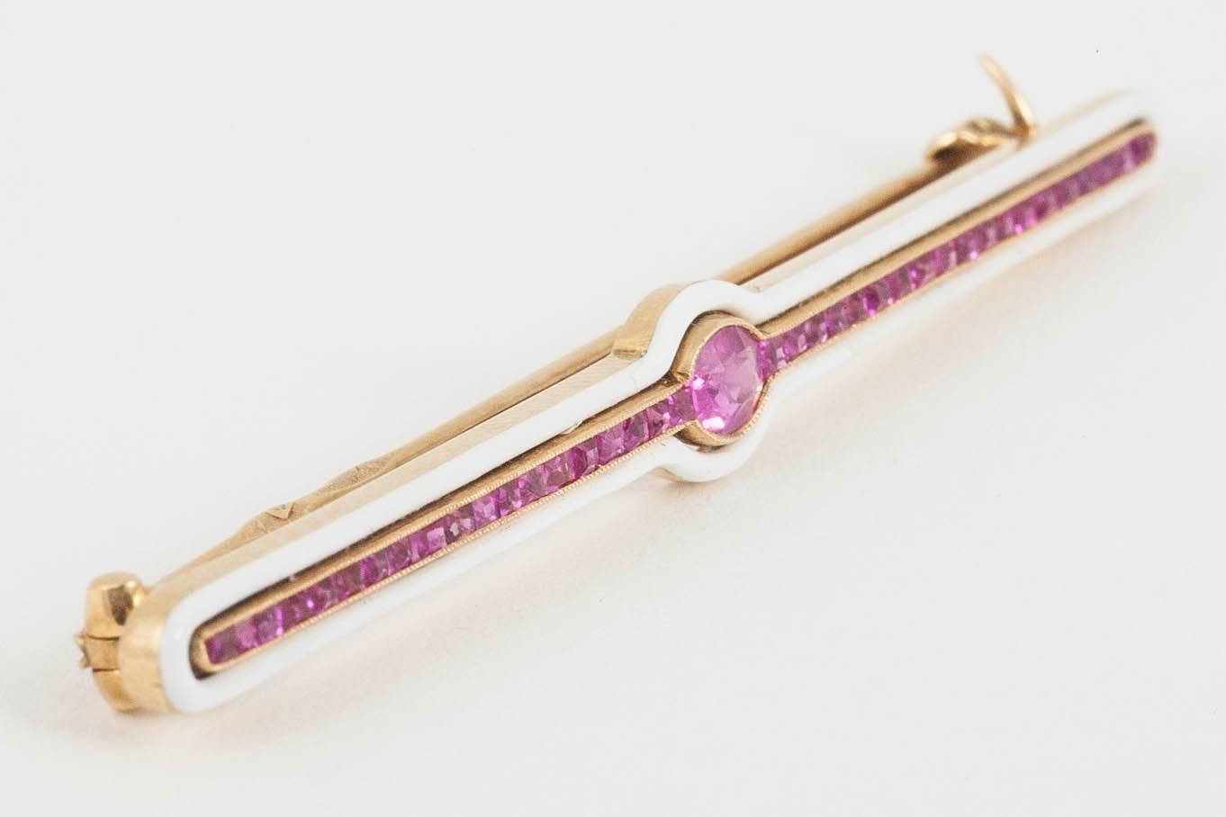 A 14 karat yellow gold antique brooch of bar shape, set with Burma rubies, surrounded with white enamel. Russian marks.
Measures 4mm in height x 58mm in length. 
Antique piece (over 100 years old) in the Edwardian style.
Early 20th century, Russian
