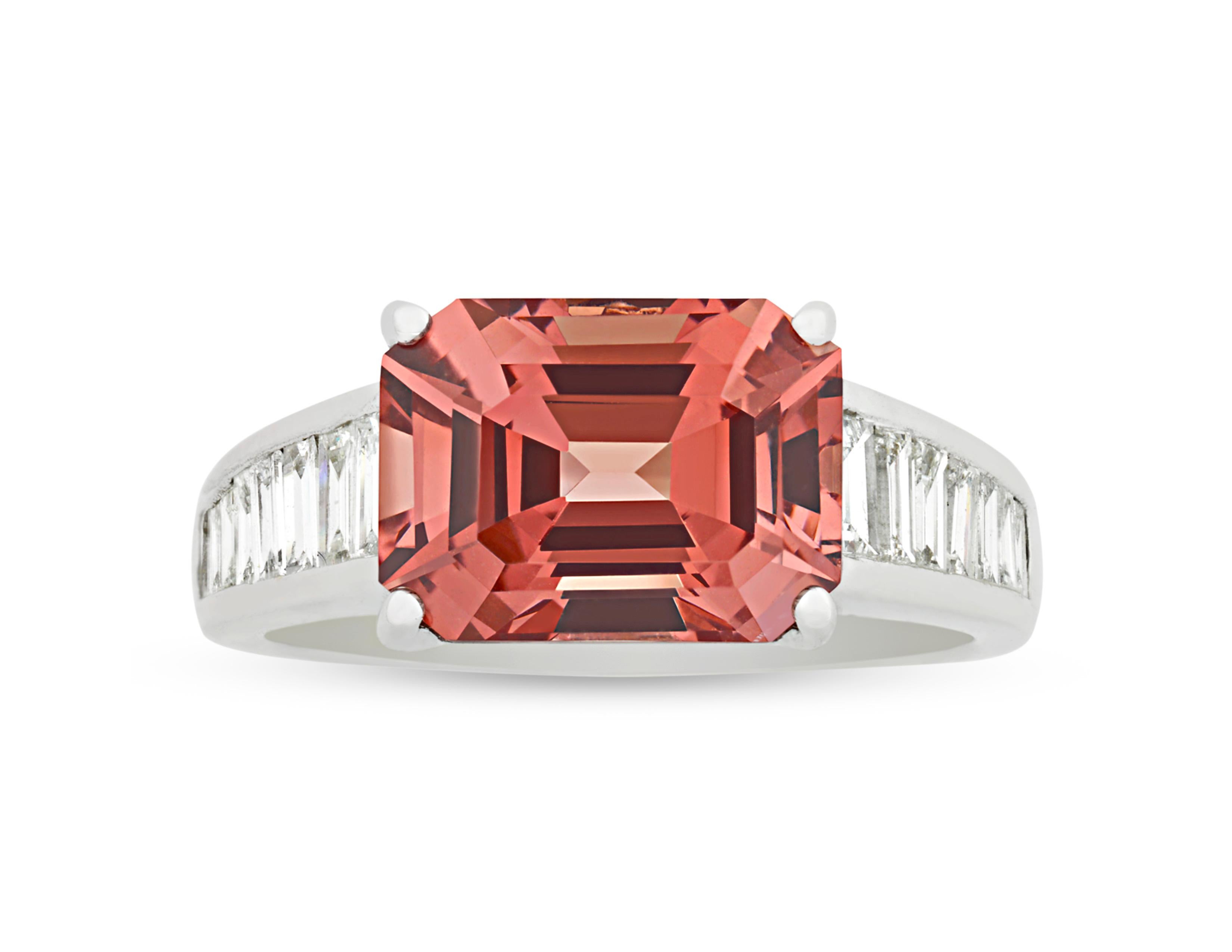 A stunning emerald-cut spinel displays its pinkish-orange hue in this ring. Hailing from the mines in Burma, the 4.62-carat gemstone is flawlessly set in 18K white gold. Diamond baguettes totaling approximately 0.66 carat lend further brilliance to
