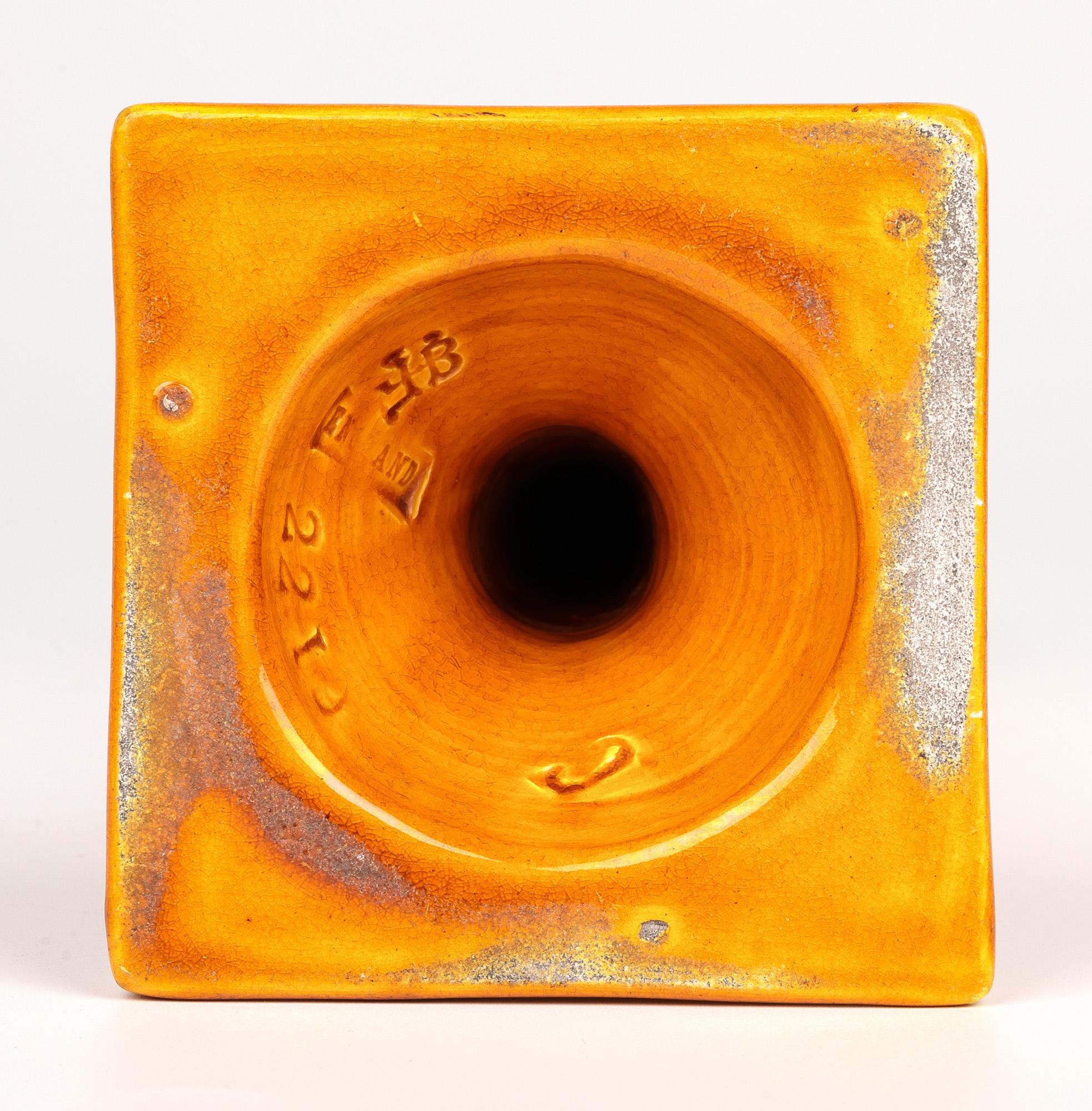 A stylish Burmantofts Faience art pottery arts & crafts gothic style candlestick decorated in yellow glazes and dating from around 1895. The elegant earthenware candlestick stands on a wide square shaped base with a narrowing square central column