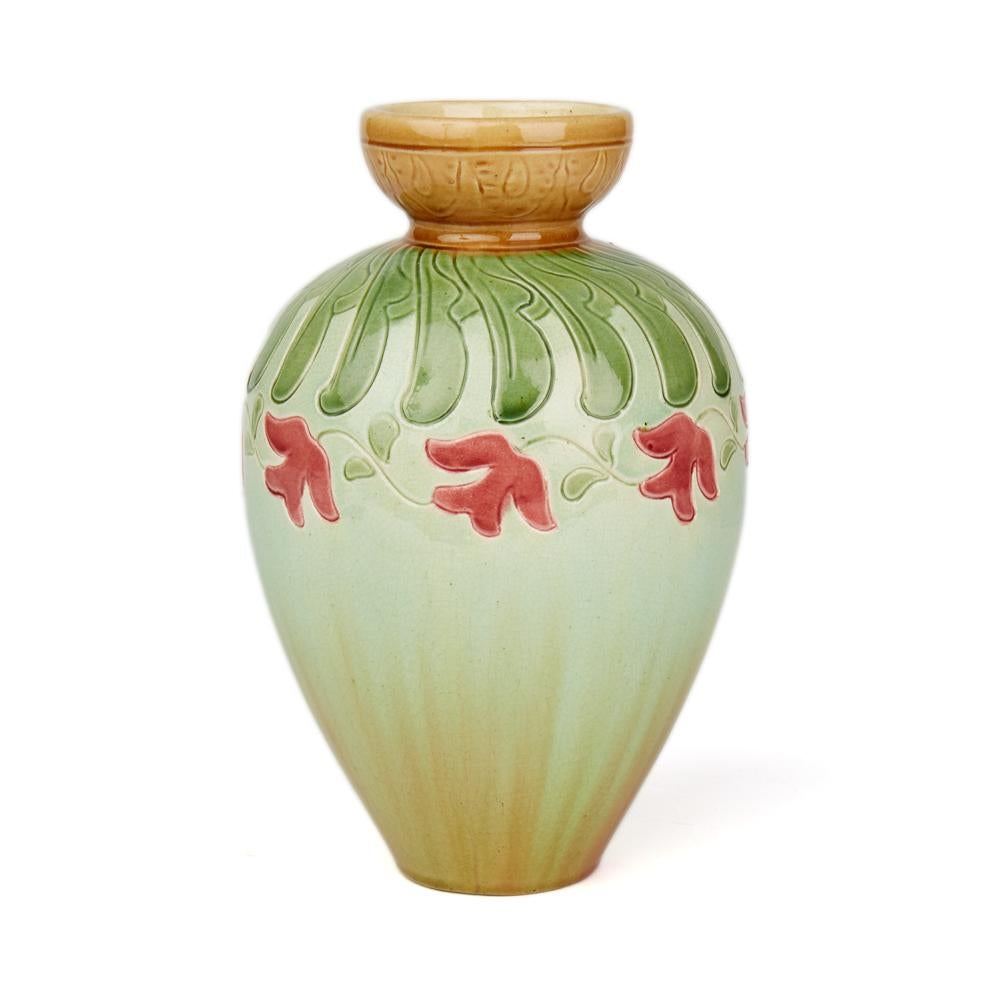 An unusual Art Nouveau Burmantofts Faience vase decorated with a frieze of pink glazed flowers dating from around 1895. The vase stands on a narrow round base with bulbous shaped body with a pinched neck and bowl shaped top. The vase is finely
