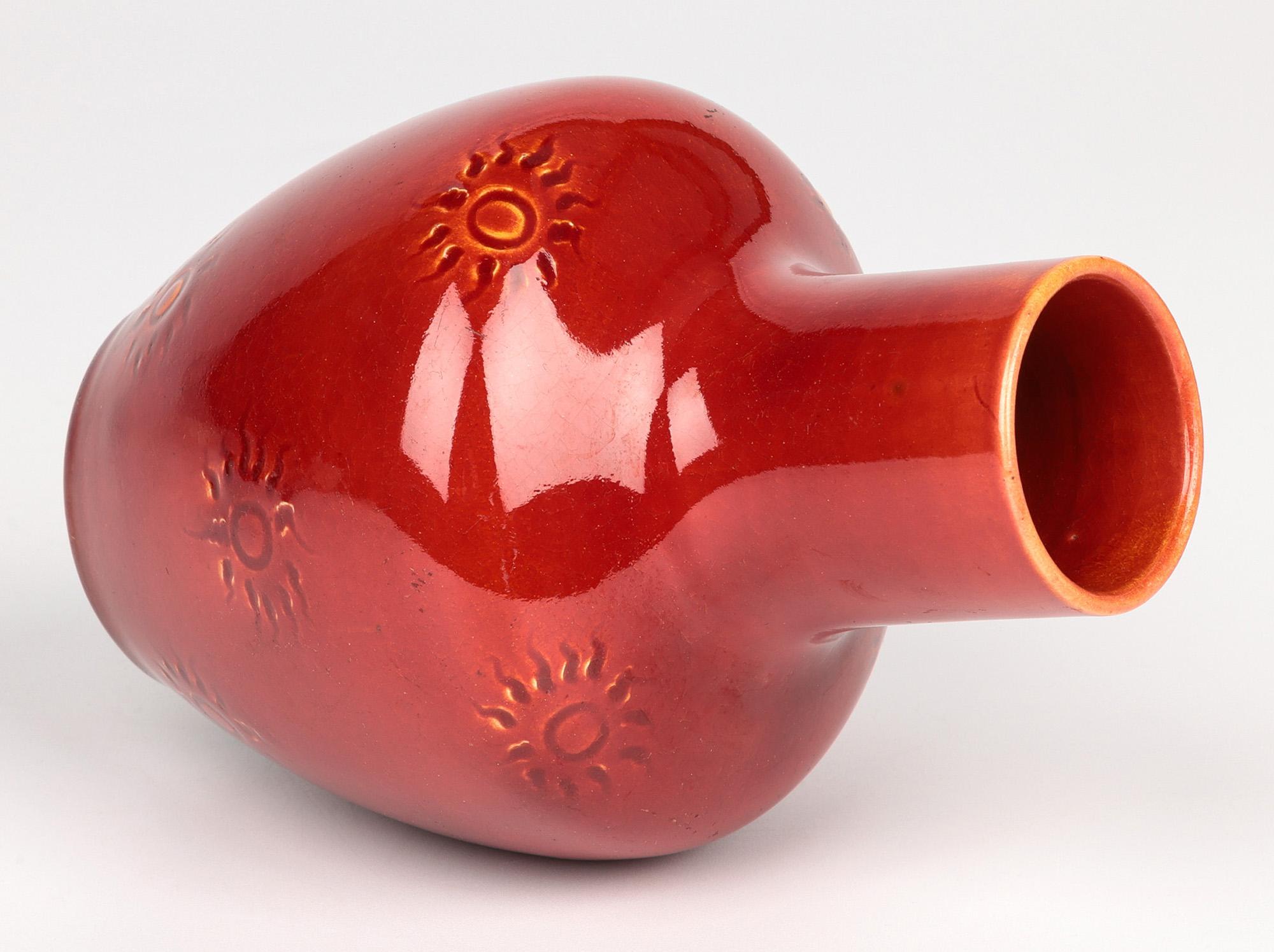 A fine Burmantofts Faience art pottery vase decorated with a sun burst pattern and dating from around 1890. The earthenware vase stands on a narrow round foot with a slightly recessed base with tall round bulbous ewer shaped body with a tall funnel