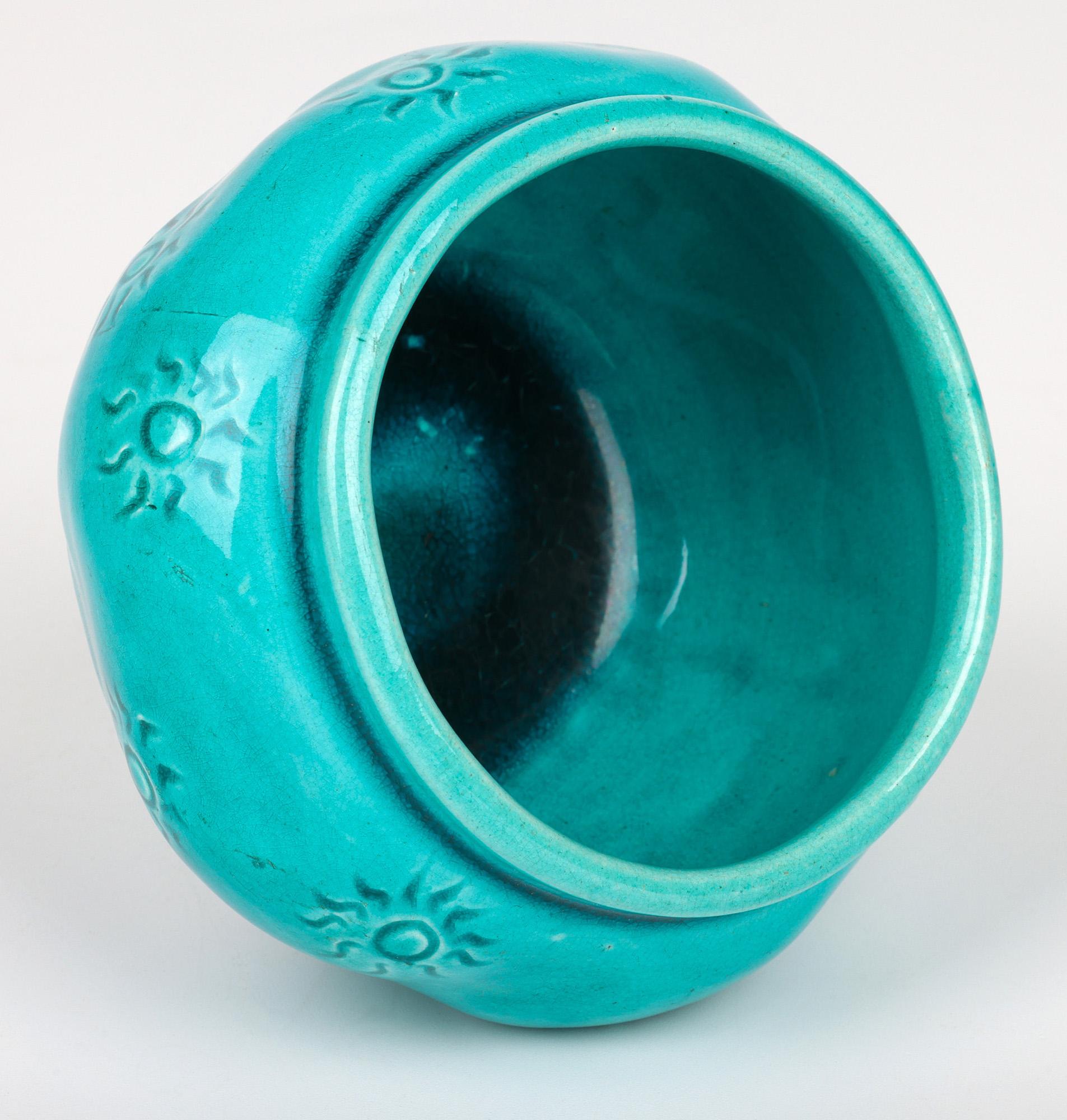 A fine Burmantofts Faience art pottery vase decorated with a sun burst pattern and dating from around 1890. The earthenware bowl shaped vase stands on a narrow round foot with a slightly recessed base with round bulbous shaped body with impressed