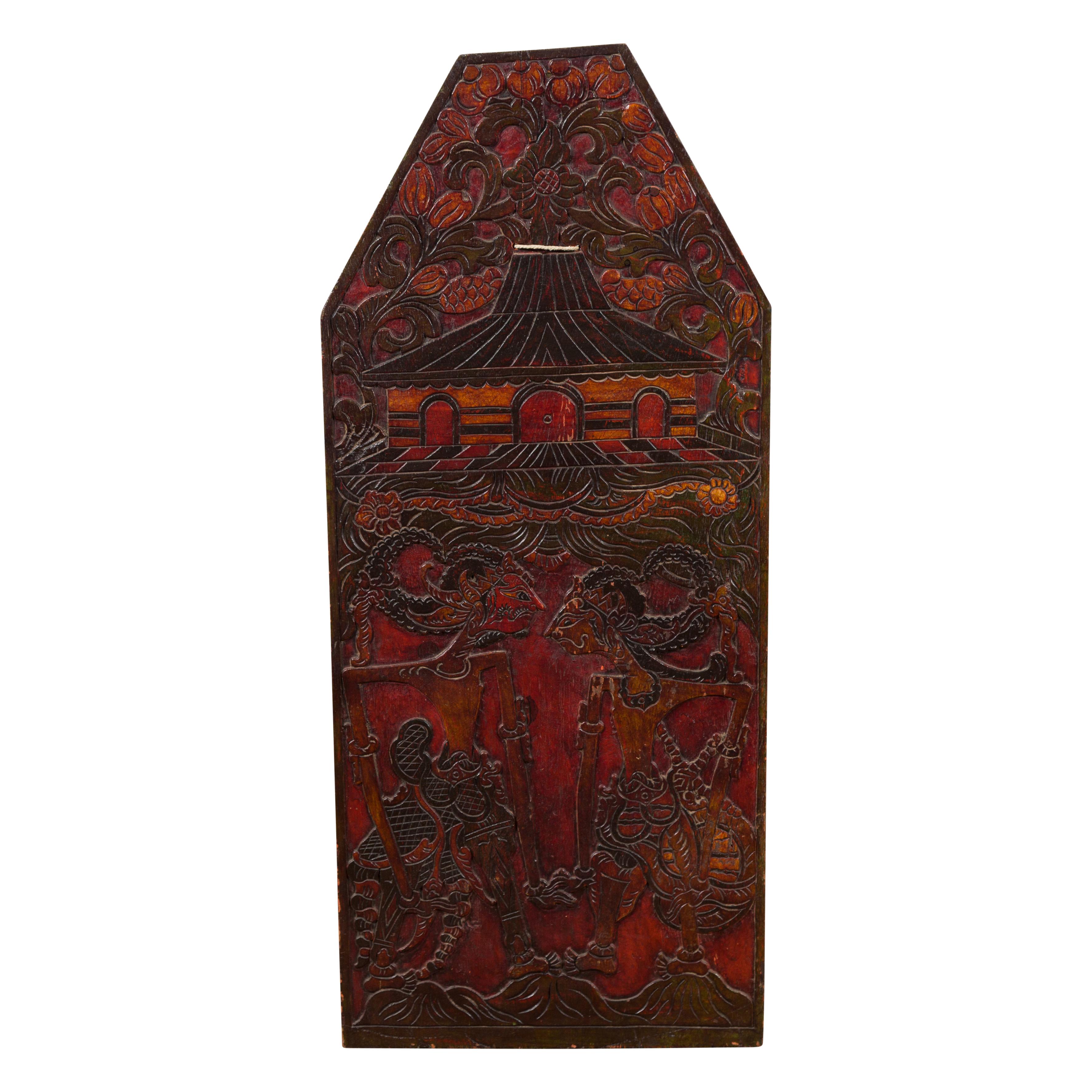 A Burmese hand-carved wooden puppet show sign from the 19th century, with red and black painted accents as well as puppets, architecture and foliage carved in low relief. This Burmese 19th century sign was hand-carved in Burma (nowadays called