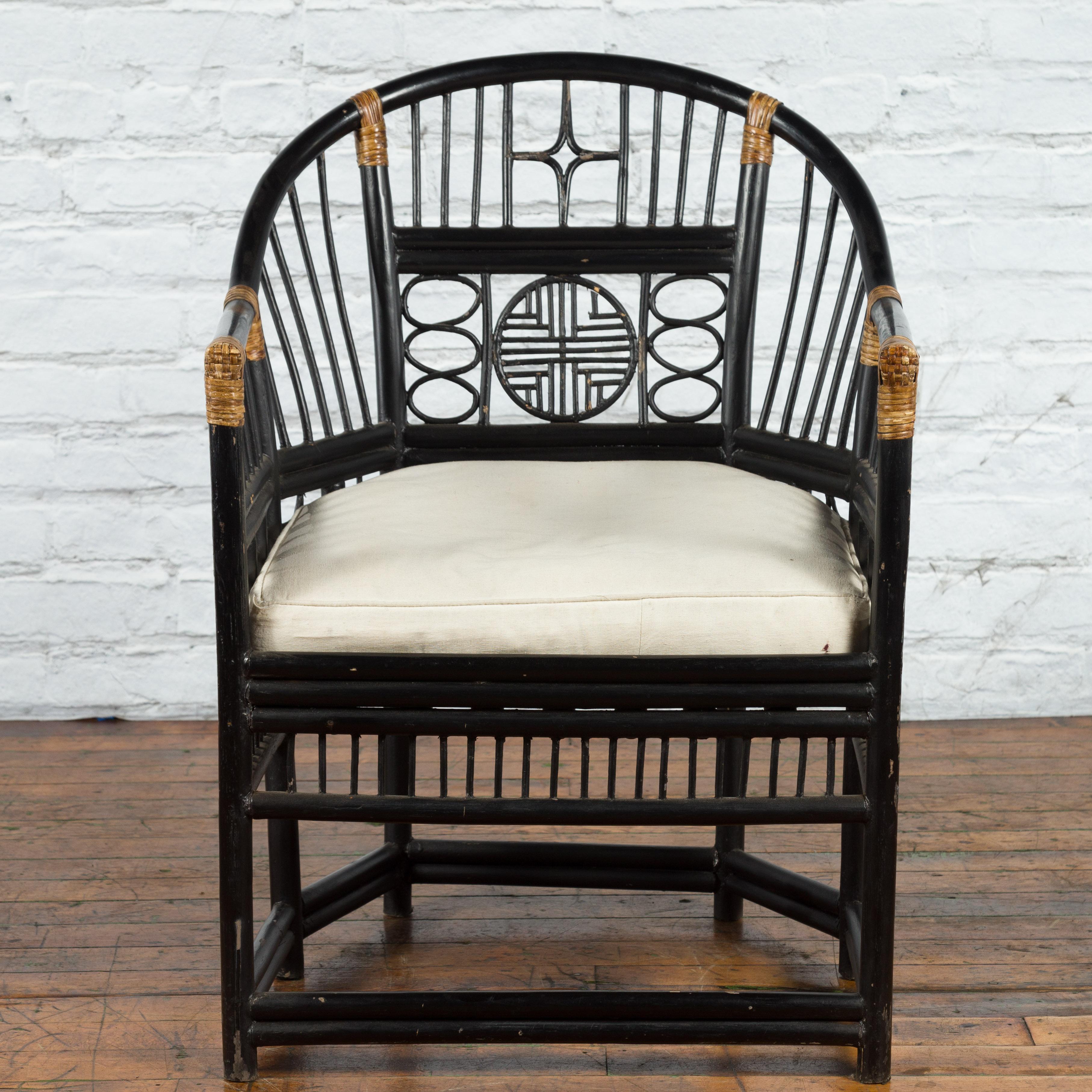 A Burmese horseshoe back black lacquered wooden armchair from the 19th century with bamboo geometric fretwork and cushion. Created in Burma during the 19th century, this armchair features an elegant horseshoe back accented in the center with a