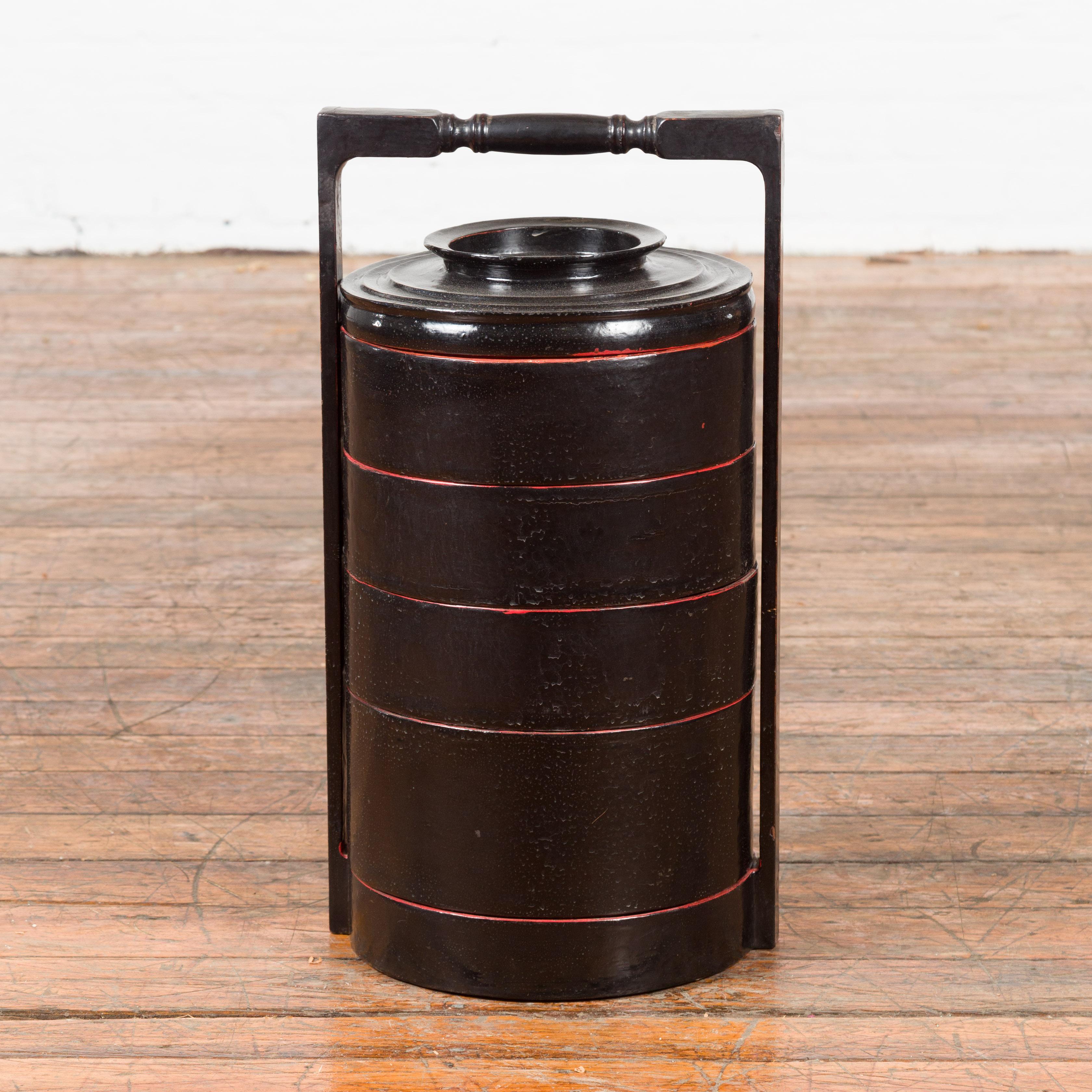 A Burmese vintage picnic basket from the mid 20th century, with black and red lacquer. Created in Burma during the midcentury period, this picnic basket features a circular black lacquered body made of five individual compartments stacked together