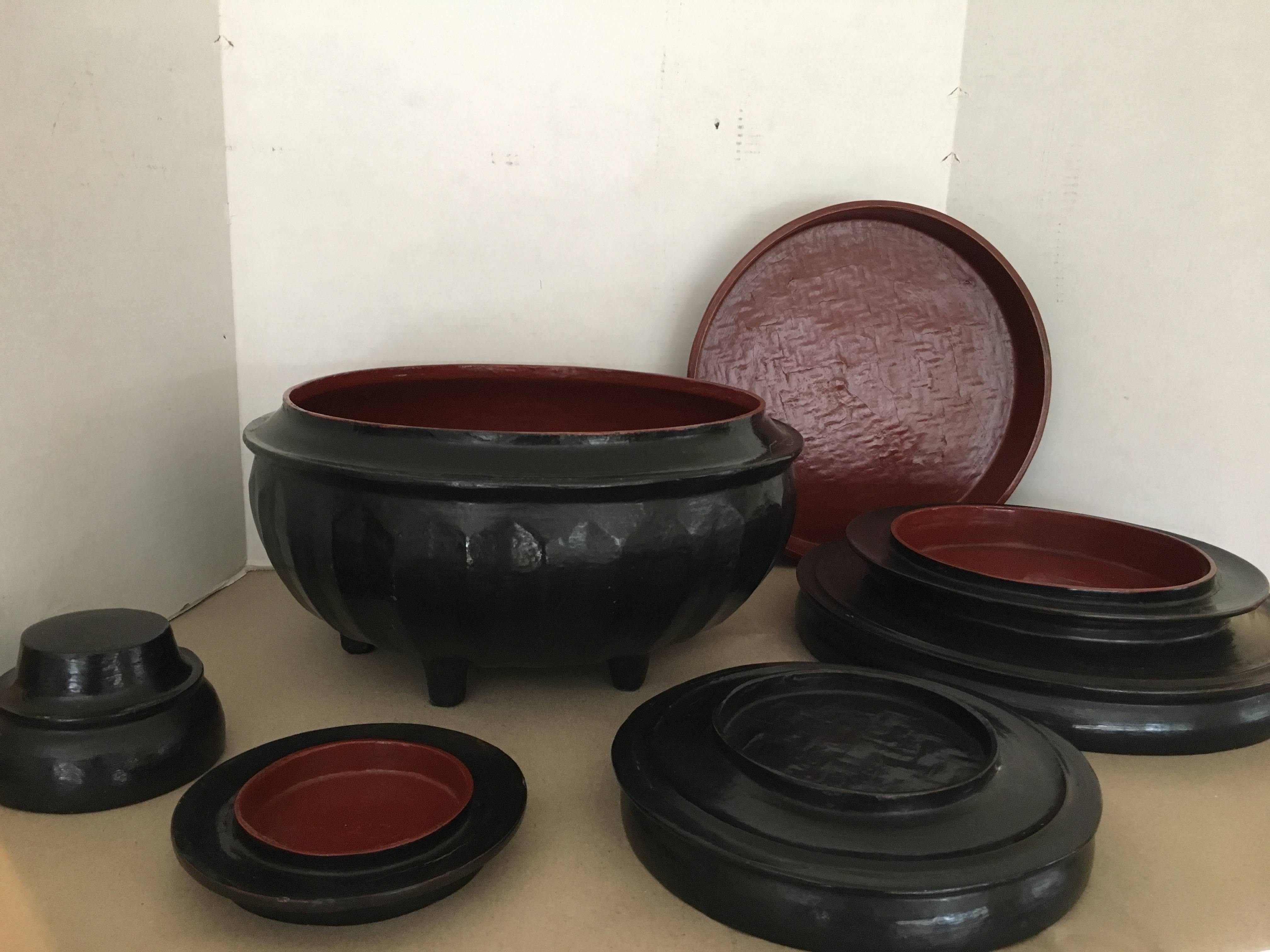 A Burmese black lacquered offering bowl called a Hsun Kwet. Used to present offerings of food at Buddhist monasteries. There are three bowls, two trays and a lid the inside is a cinnabar color.