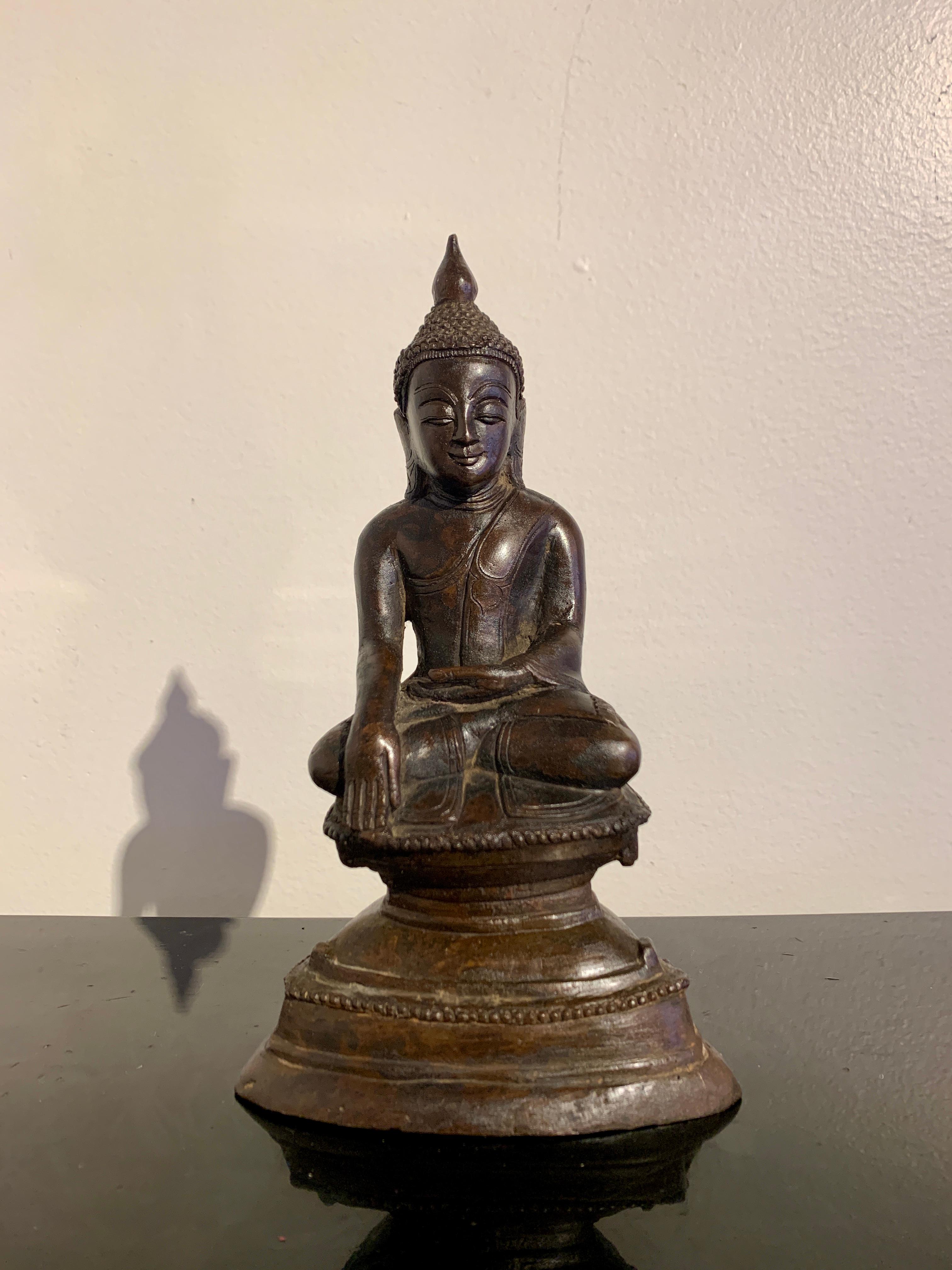 A small and charming Burmese cast bronze Buddha in the Ava style, late 19th or early 20th century, Myanmar (Burma).

The image depicts the historical Buddha, Shakyamuni, seated in full lotus position, his hands in bhumisparsha mudra, the gesture