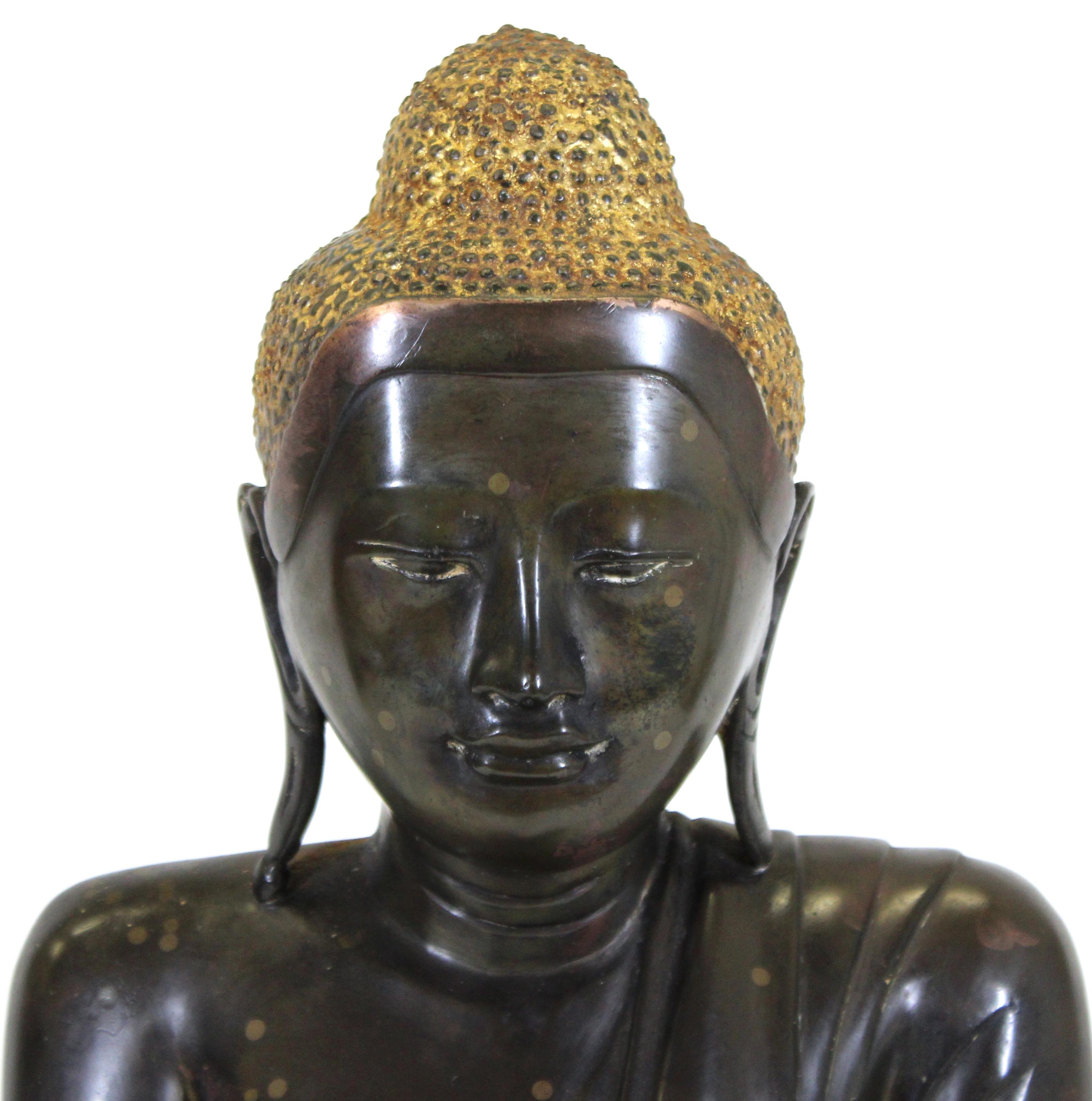 Burmese bronze sculpture of a seated Buddha with partial gilding, with his hands in bhumisparsha mudra, the gesture of calling the earth to witness, symbolizing the moment of the Buddha's enlightenment. The piece was likely made in the early 20th