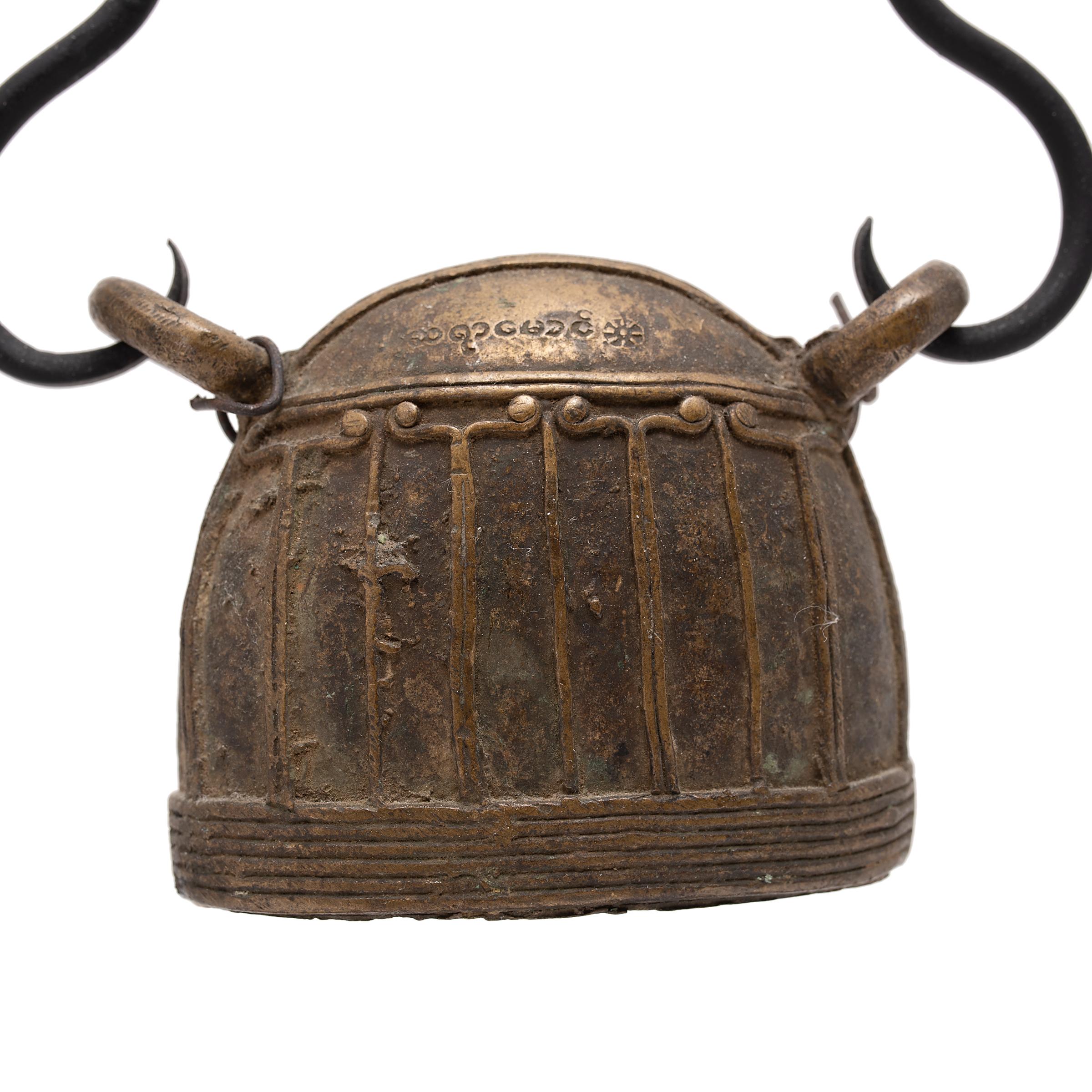 This large Burmese bell is known as hka-lauk and was used to track the movement of a livestock animal, strung from a collar by the two loops at the top. Dated to the 19th century, the bell was cast of bronze using the lost wax method with a