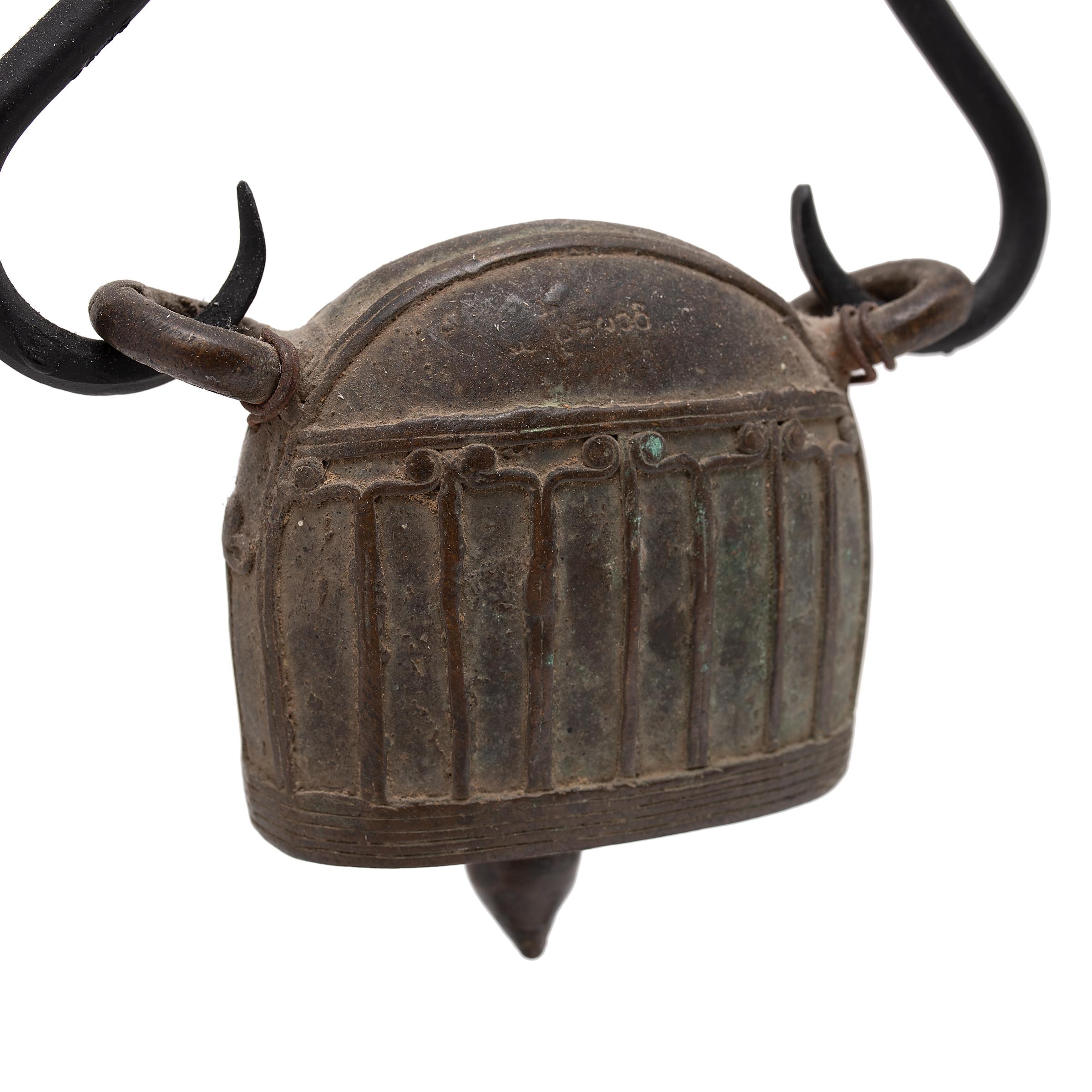 This large Burmese bell is known as hka-lauk and was used to track the movement of a livestock animal, strung from a collar by the two loops at the top. Dated to the 19th century, the bell was cast of bronze using the lost wax method with a