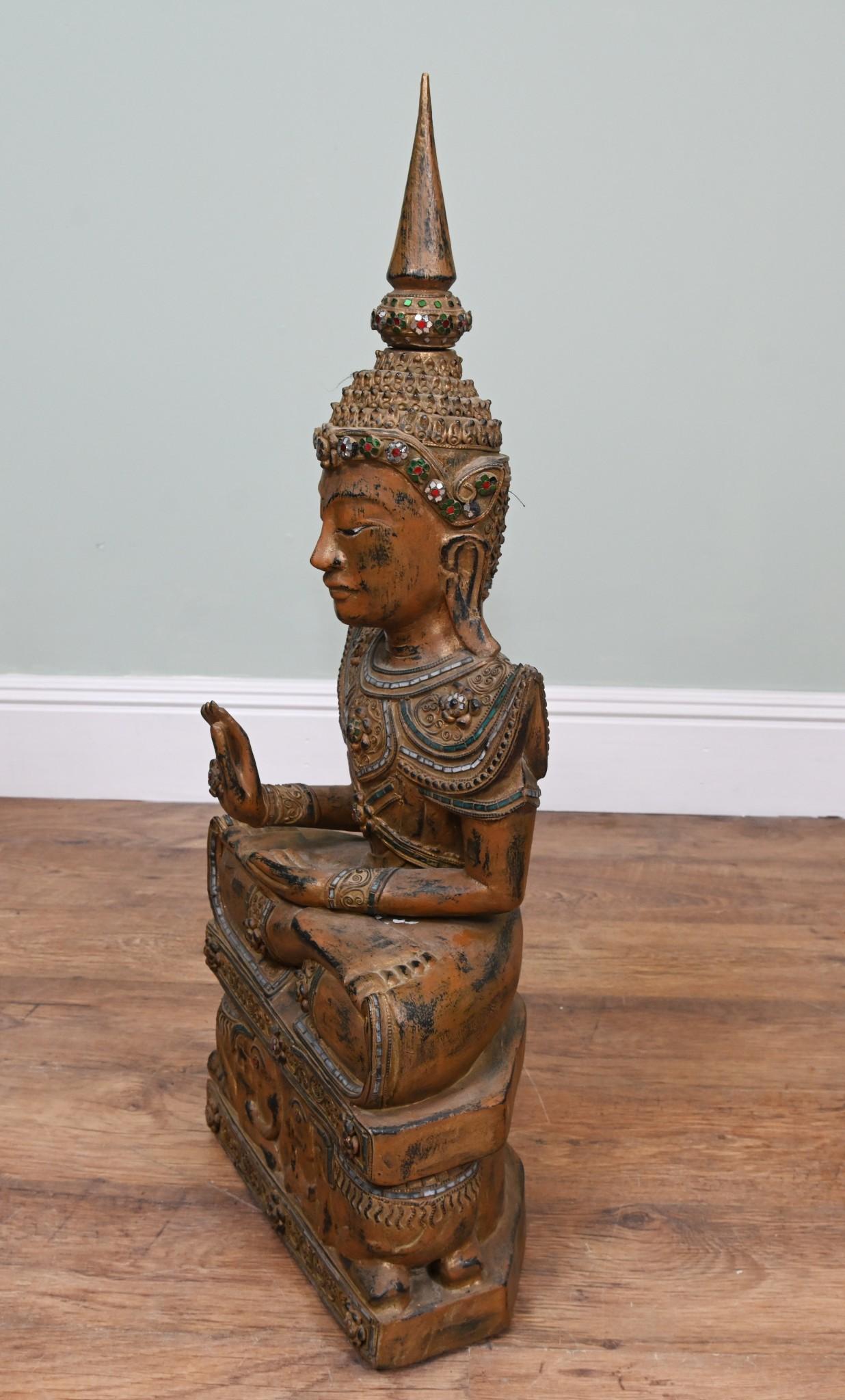 Buda birmano sentado, único, tallado en madera pintada de dorado y verde, sentado en postura de meditación
Cada parte de este buda está decorada con piedras verdes, rojas y espejadas
La base de este buda está tallada con elefantes
Levanta la mano