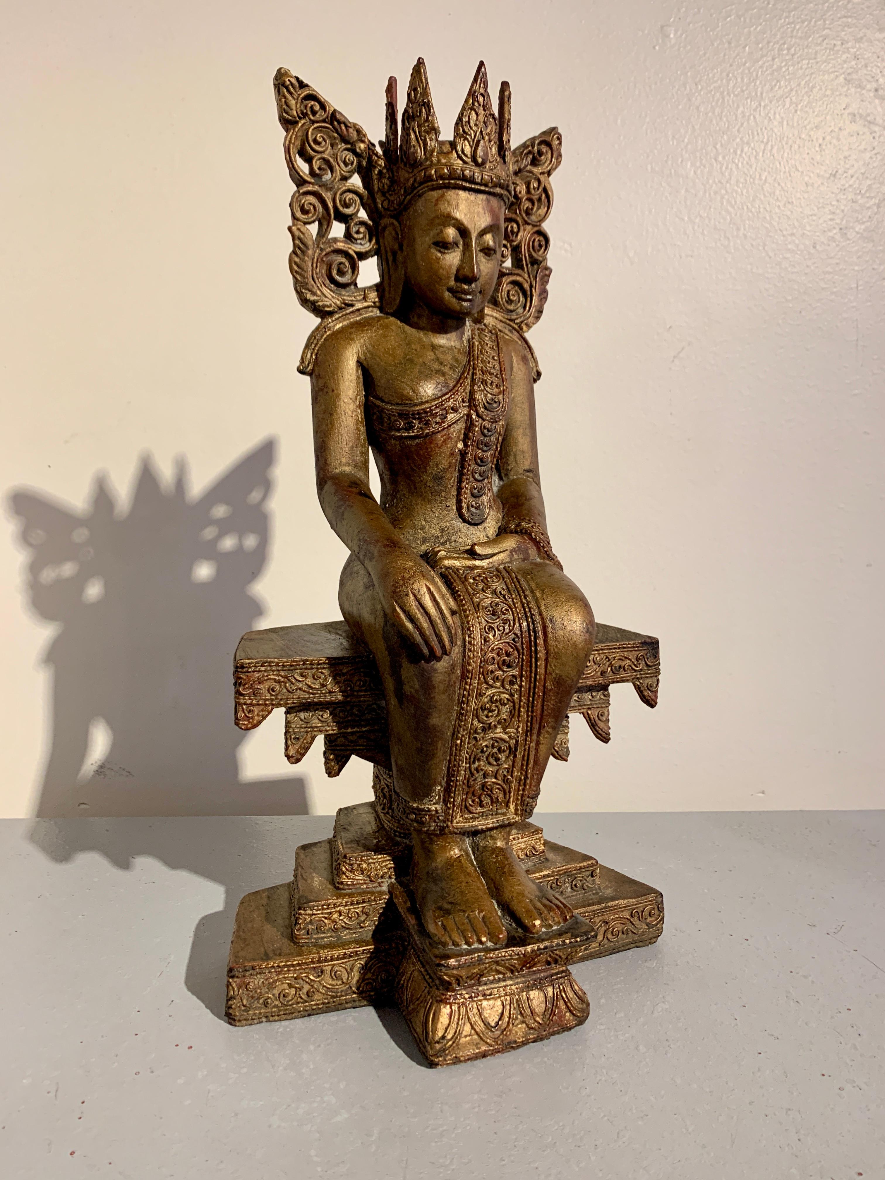 A sublime Burmese carved, lacquered and gilt hardwood crowned Buddha seated in a 