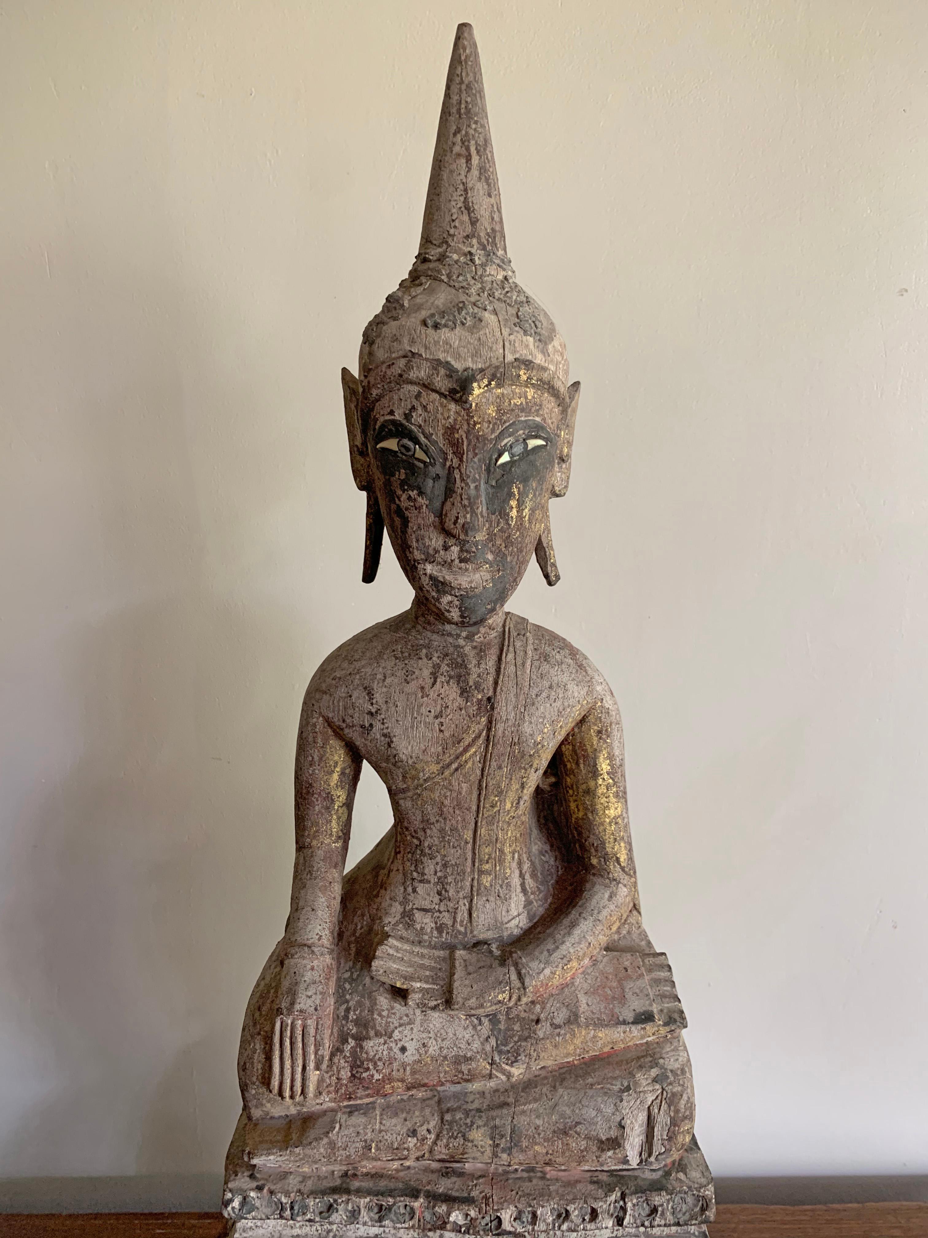 This buddha is a hand-carved from wood and originates from Burma, modern day Myanmar. It once featured an elaborate gilded finish (covered in gold leaf), however much of this has worn away over the decades. However there are faint traces of the