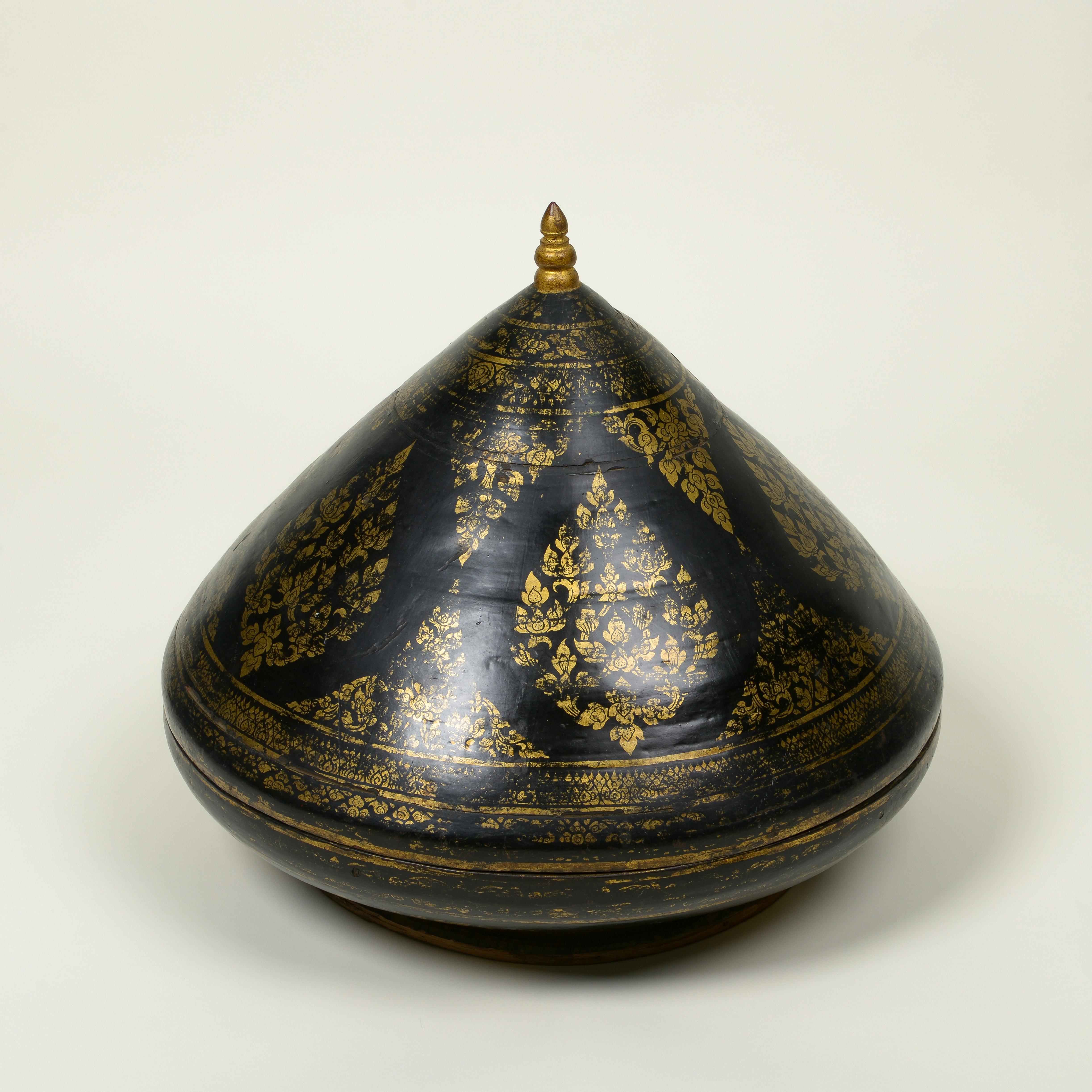 Il coperchio conico è sormontato da un terminale a pomello e finemente decorato in doratura con fogliame a volute; l'interno è in lacca cinabro.

Questo tipo di recipiente cerimoniale è un daung-baung kalat e veniva utilizzato per presentare