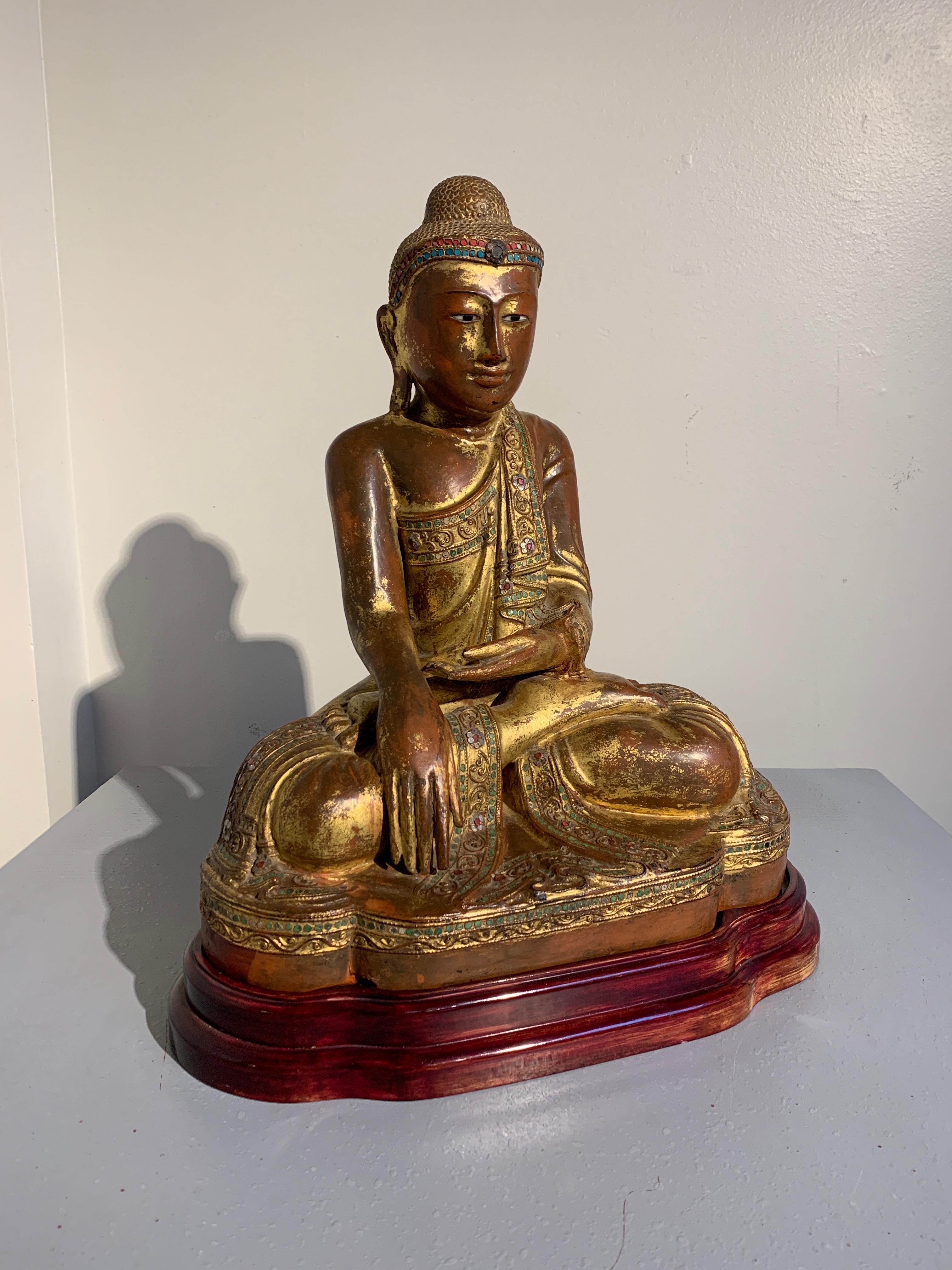 A charming Burmese carved teak figure of the Buddha, lacquered, gilt and embellished with glass 