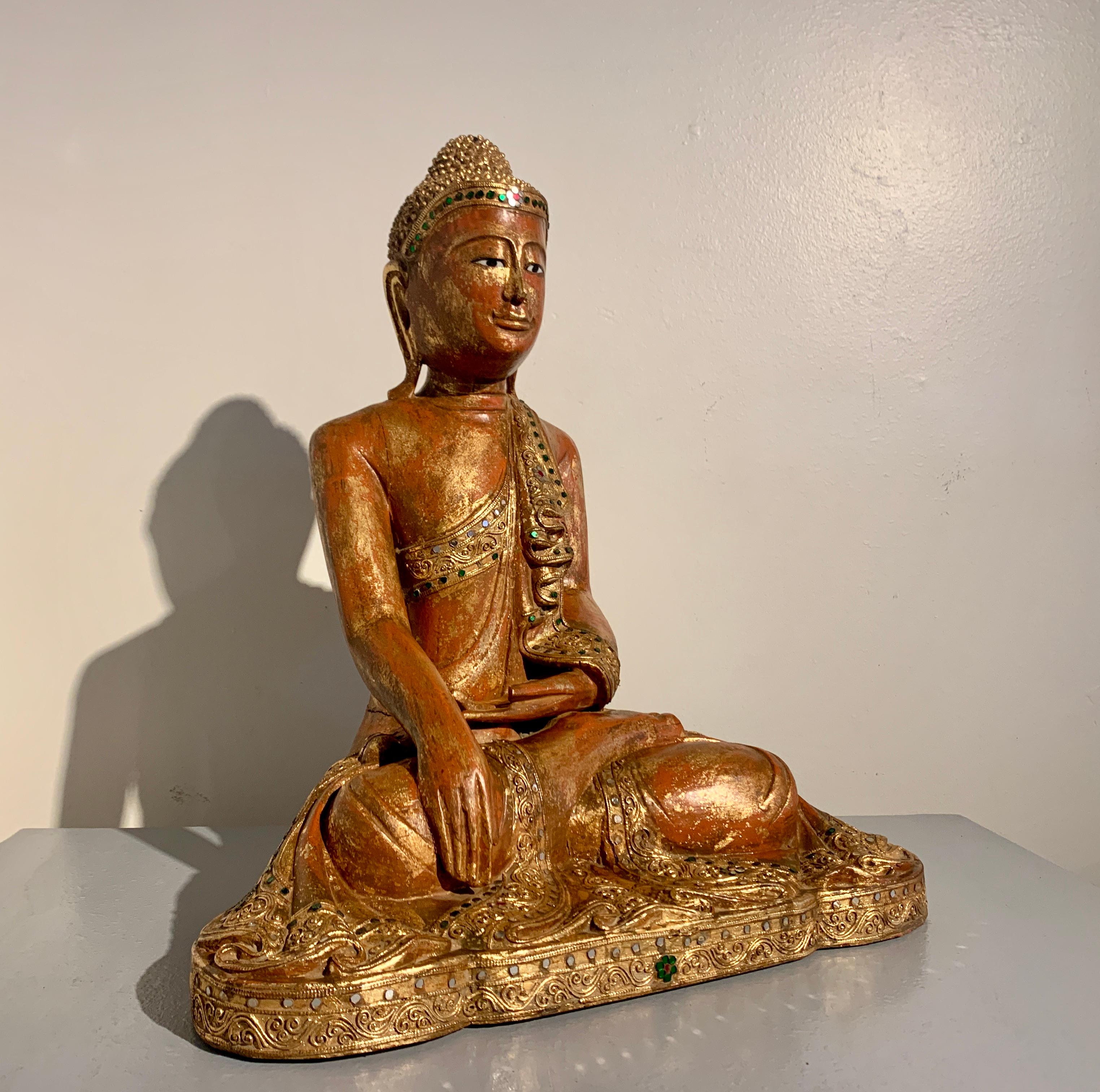 Magnifique et sereine figure de Bouddha assis en bois de teck birman sculpté, de style Mandalay et d'époque, fin du XIXe siècle, Birmanie (Myanmar).

Cet élégant Bouddha est représenté assis sur une courte base dans la position du lotus, la plante