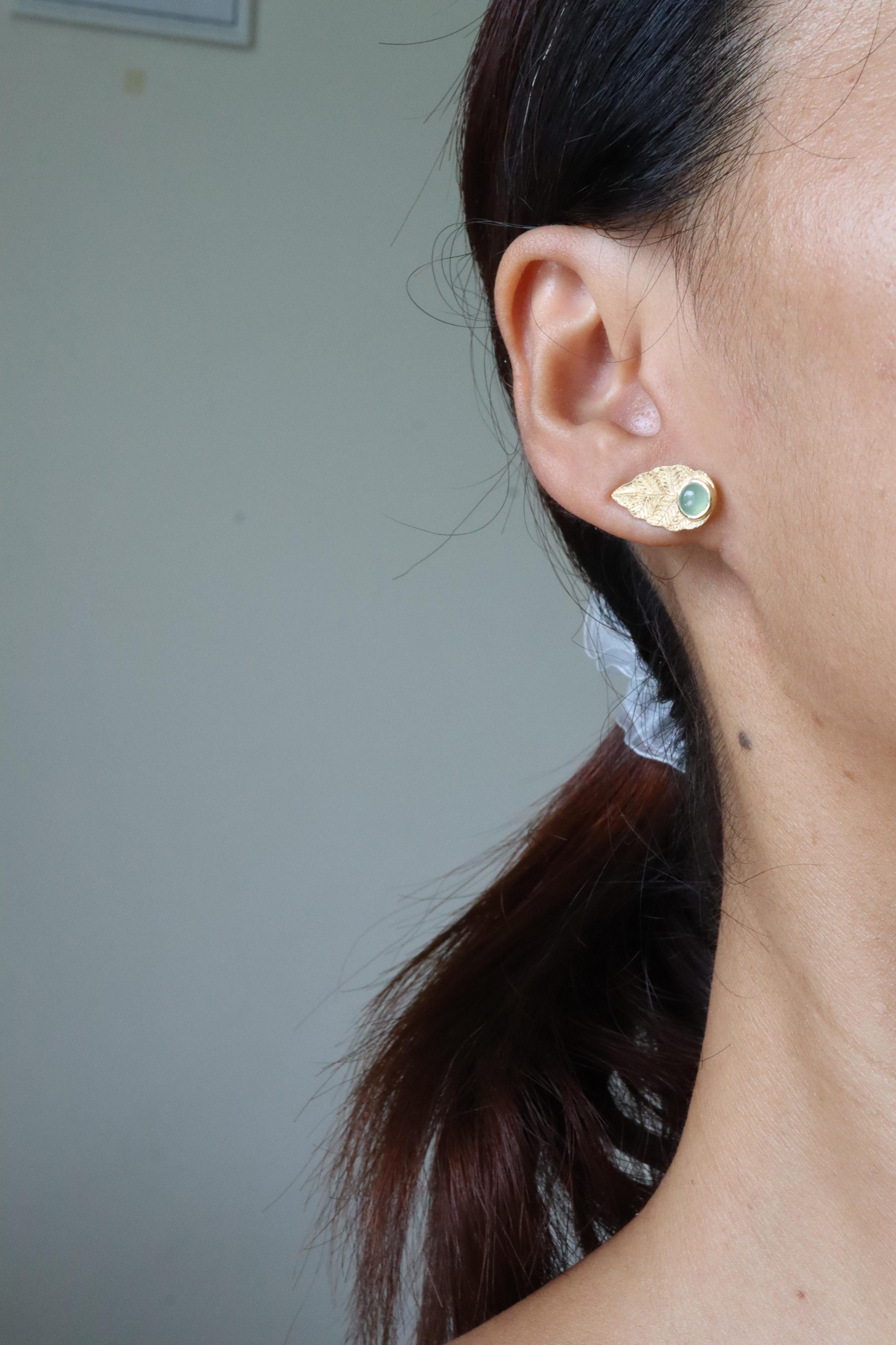 These earrings are crafted in 18k solid gold and feature a beautifully textured, brushed finish that mimics the look of natural leaves. They are accented with natural Type A jade, adding value and uniqueness to the design. Each earring showcases a