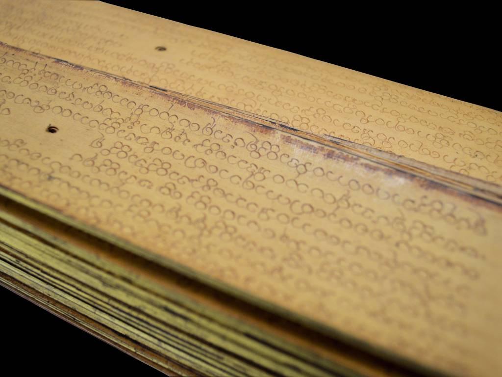 A 19th century Burmese palm leaf pali prayer manuscript referred to as paysar in Myanmar. This palm leaf manuscript has had special treatment, the wooden end covers are red lacquered with the edges of the palm leaf pages gilded, the wooden ends of