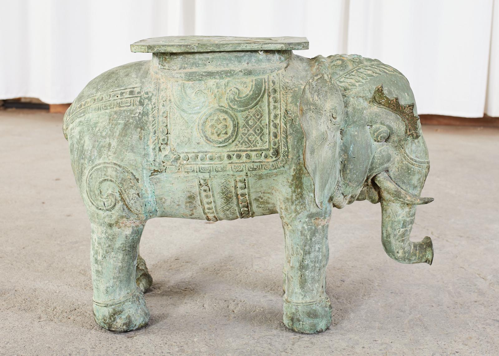 Well patinated bronze elephant garden stool or drinks table from Burma (Myanmar) The elephant features an aged verdigris patina with intricate details. His body is caparisoned and his head has large lotus blossom ears and tusks. He is topped with a