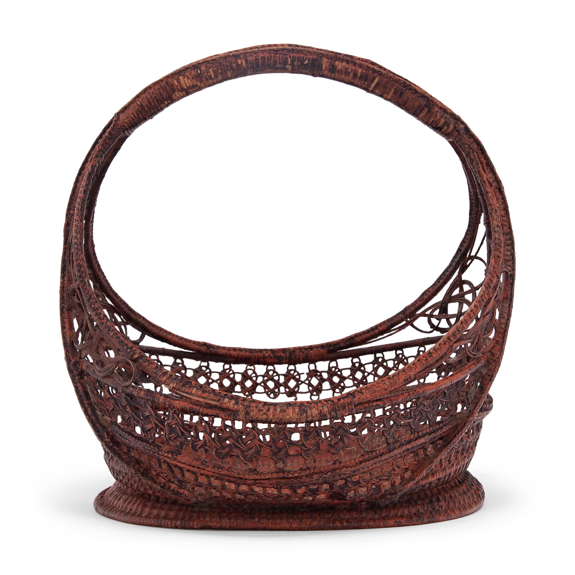 This gorgeous Burmese basket is expertly woven of thin strips of split bamboo and colored by layers of black and red lacquer. With curvilinear form and a high, arched handle, the basket seems to be a variation of those traditionally used to carry